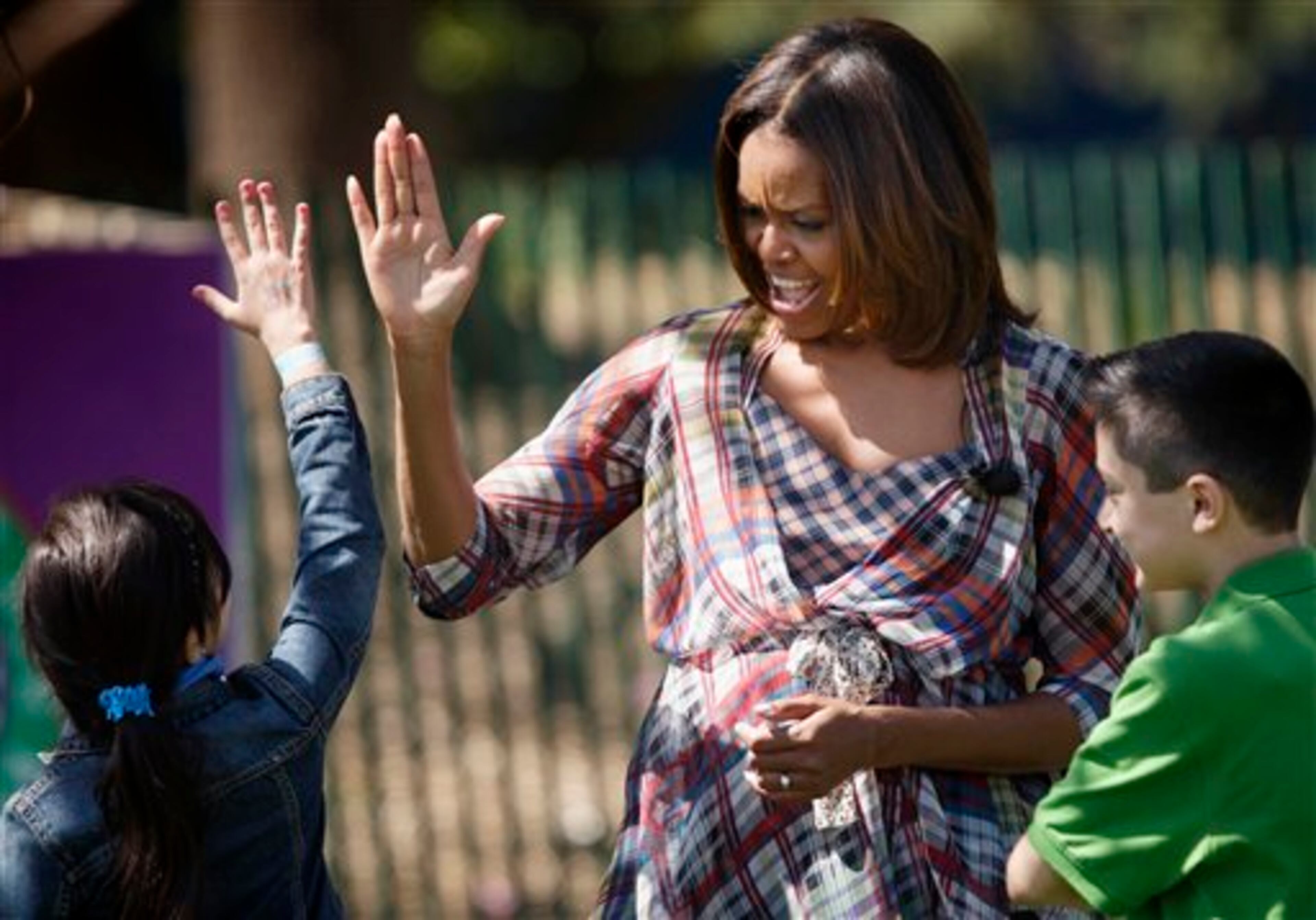 First lady Michelle Obama gets a high-five from some youngsters after reading to them during the annual White House Easter Egg Roll, Monday, April 21, 2014, on the South Lawn of the White House in Washington. This year's event features live music, cooking stations, storytelling, and of course, some Easter egg rolling. (AP Photo/J. Scott Applewhite)