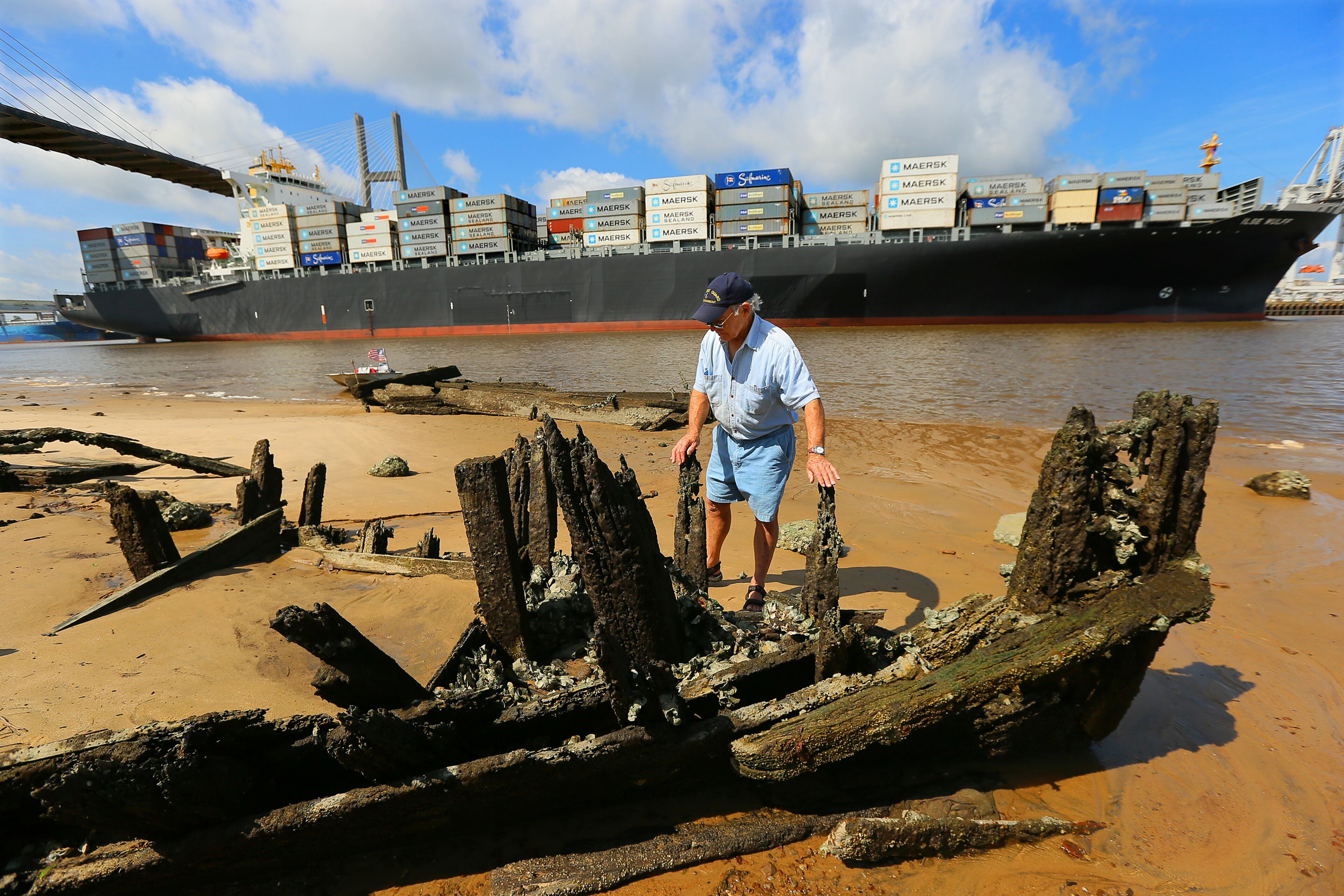 Savannah River scavenger Charlie Ellis searches for artifacts around the shipwreck called "Dave's Derelict" while a container ship passes beneath the Talmadge Memorial Bridge coming into port in Savannah. The rusted century-old tugboat with iron boiler (far left) rises out of the water twice a day, when tides are low, a reminder of Georgia's lost maritime history.