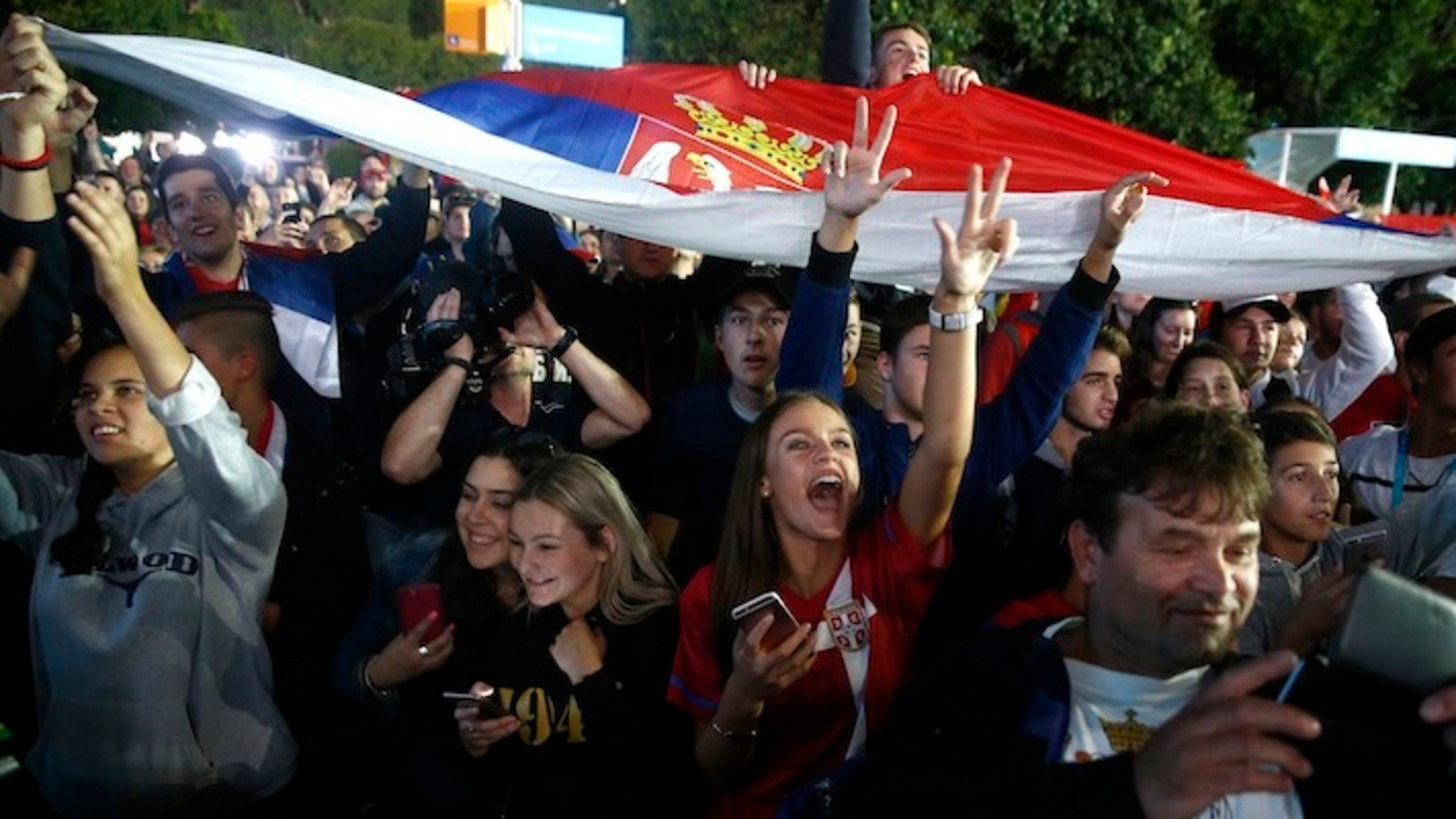 Fans cheer as Novak Djokovic of Serbia waves to spectators from a television studio after defeating Andy Murray of Britain in the men's singles final at the Australian Open tennis championships in Melbourne, Australia, Sunday, Jan. 31, 2016.(AP Photo/Rafiq Maqbool)