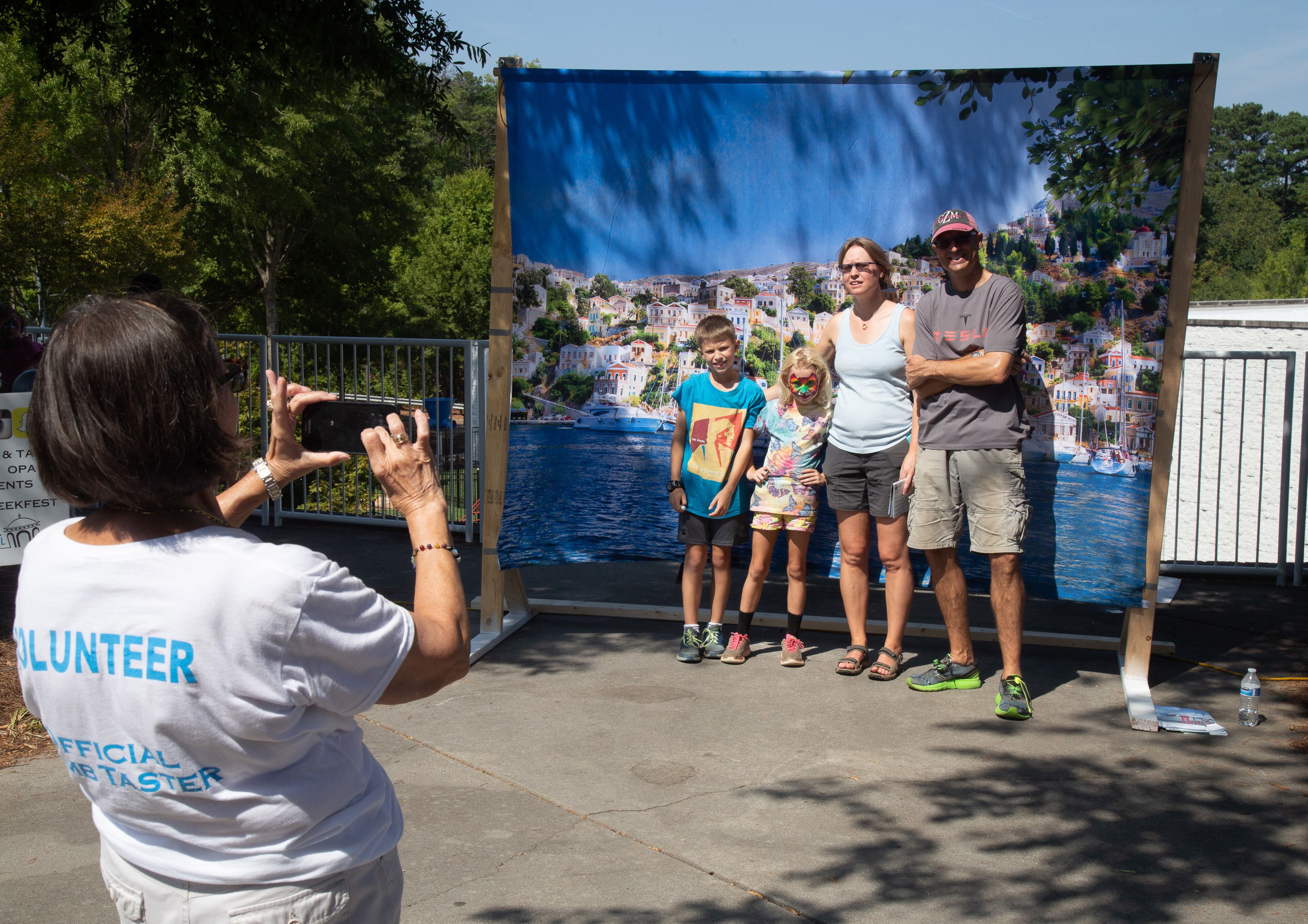 Volunteer Vickie Klems takes photographs of people in front of a Greek seen during the Atlanta Greek Festival on Sunday, September 29, 2019. STEVE SCHAEFER / SPECIAL TO THE AJC