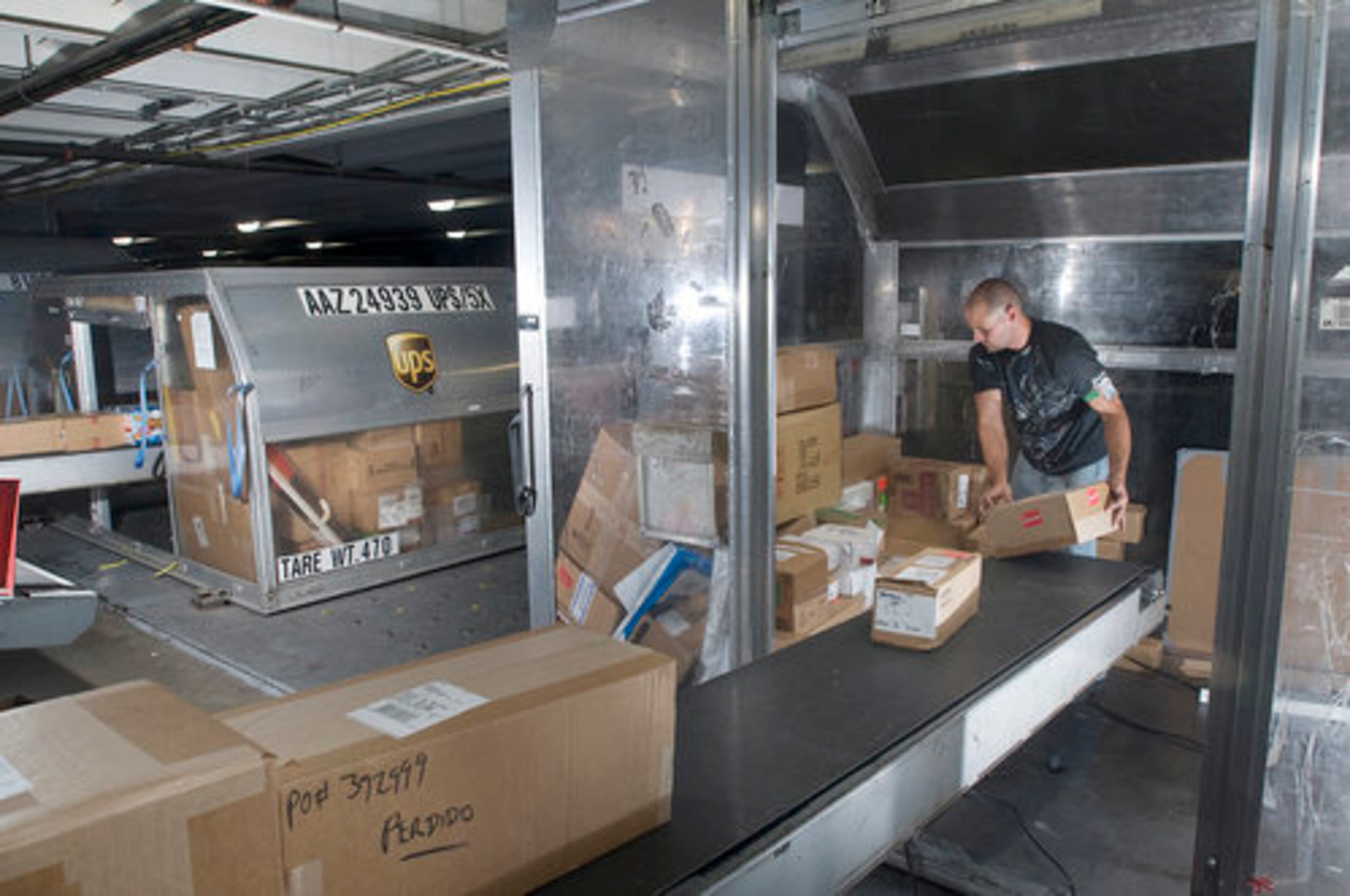 Duran Drake places boxes onto a sorting conveyor belt. To get from inbound plane to connecting flight, 110 miles of conveyor belt take packages on a ride that would make Six Flags proud.