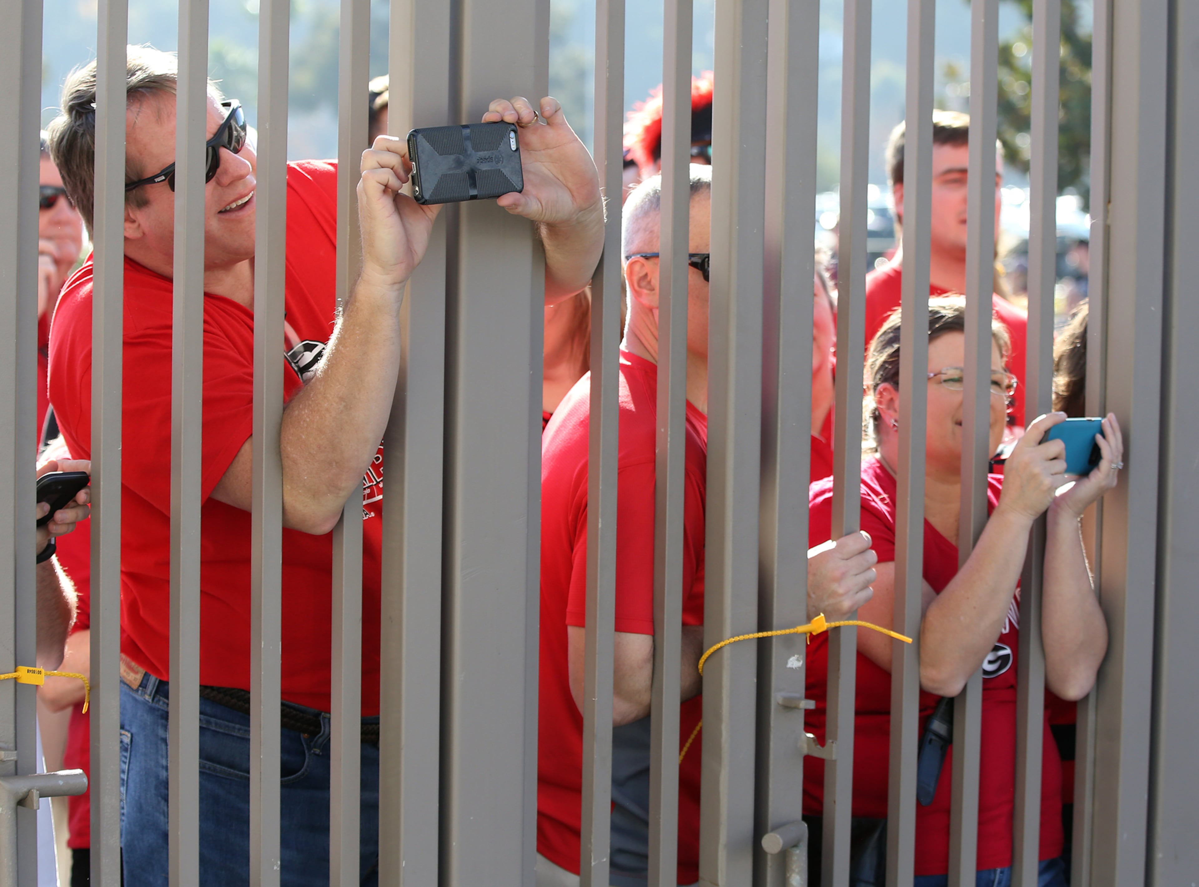 December 31, 2017 Pasadena: Georgia fans angle for a view and snap photos through the fence while the Georgia official team photo is taken at Rose Bowl Stadium on Sunday, December 31, 2017, in Pasadena. Curtis Compton/ccompton@ajc.com