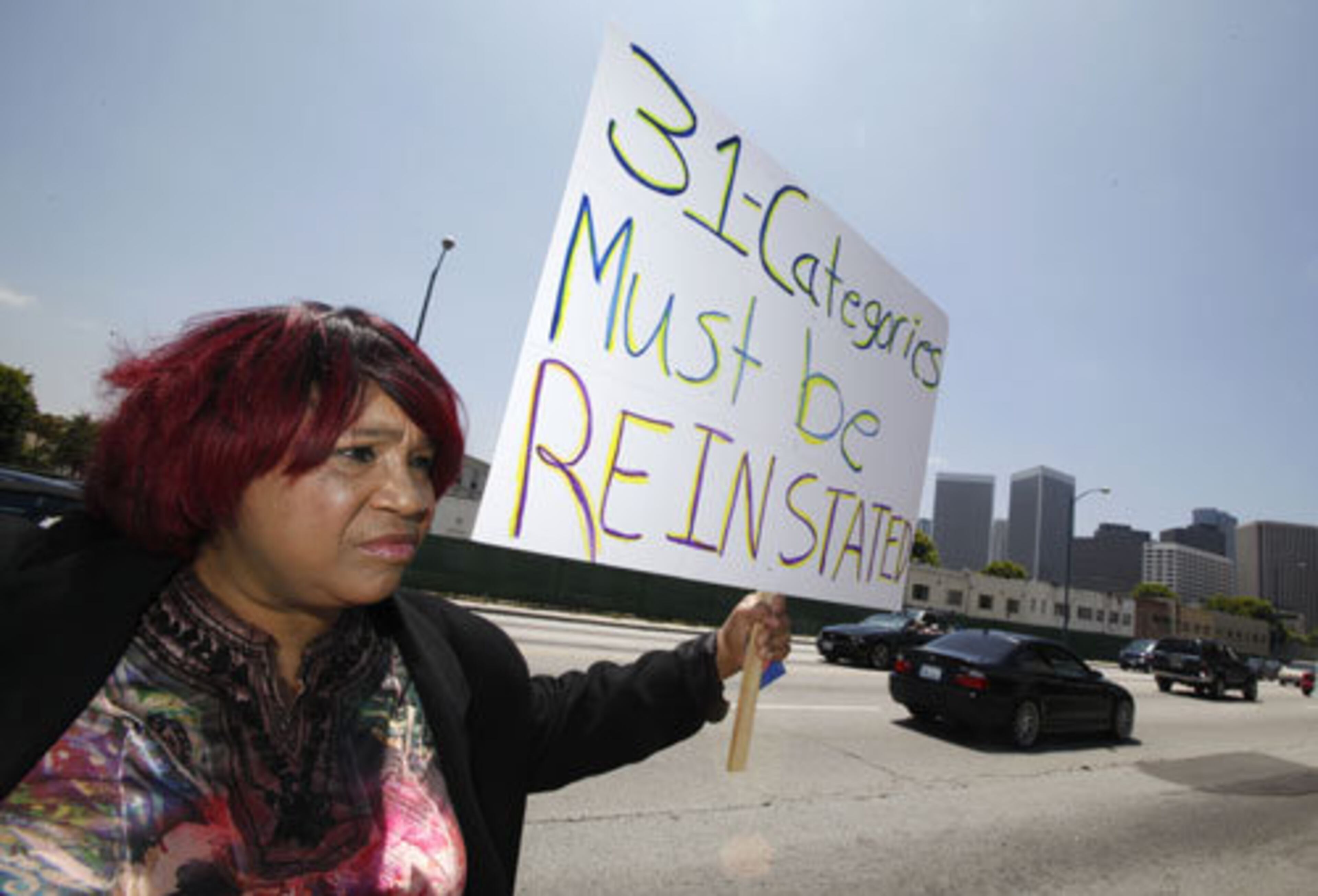 Pepper Mashay, also known as Sista Jean, holds a sign saying "31 categories must be re-instated," referring to the reductions that demonstrators say unfairly target ethnic music.