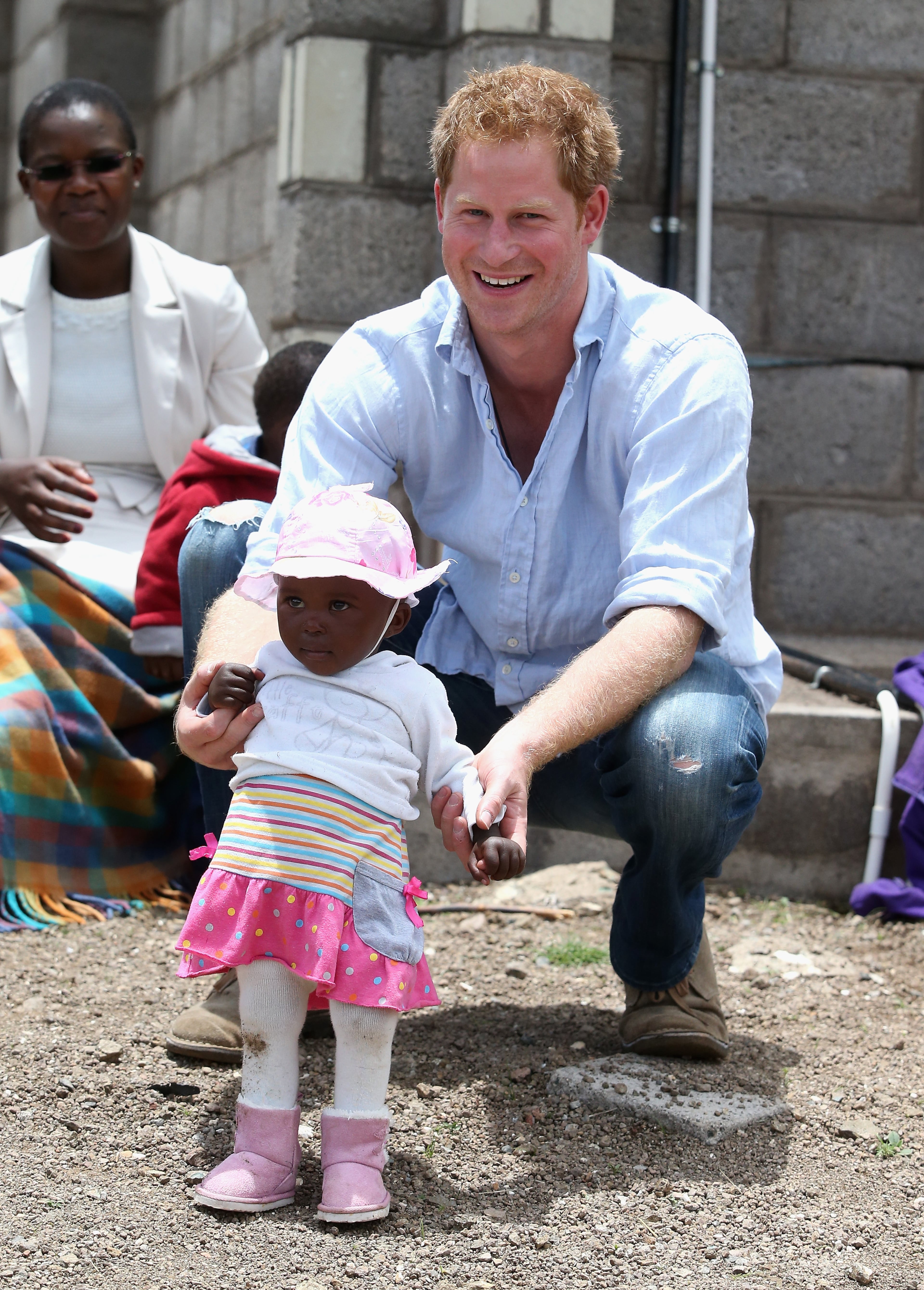Prince Harry holds a baby during a visit to a herd boy night school constructed by Sentebale on December 8, 2014 in Mokhotlong, Lesotho. Prince Harry was visiting Lesotho to see the work of his charity Sentebale. Sentebale provides healthcare and education to vulnerable children in Lesotho, Southern Africa. The particular theme of his visit was to check on the progress of the Mamohato Childrens Centre which will provide vital support to children affected by HIV. Prince Harry founded Sentebale (which means Forget Me Not in Sesotho) with Prince Seeiso in 2006. (Photo by Chris Jackson/Getty Images for Sentebale)