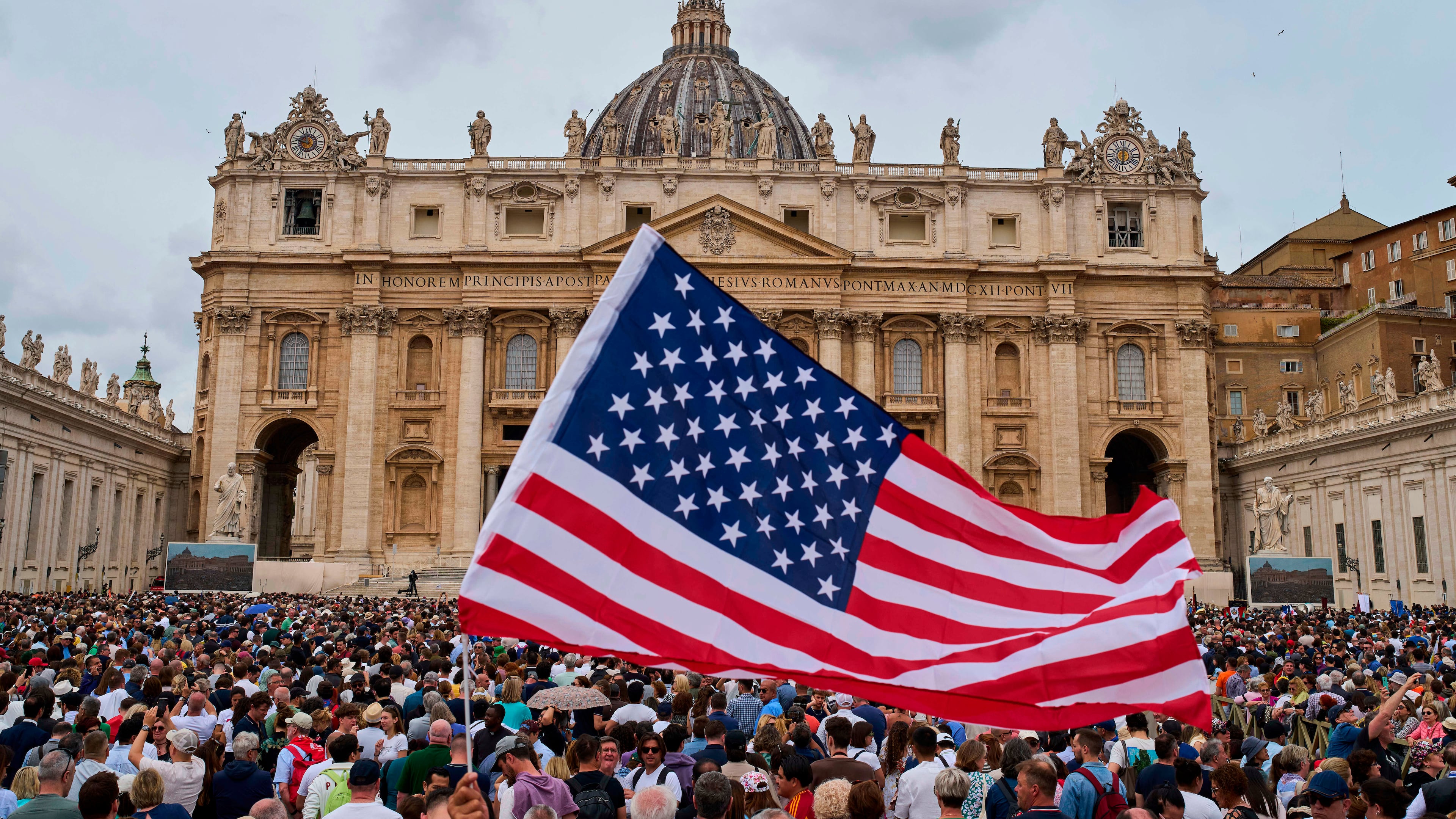 FILE - A flag from the United States waves in the crowd as Pope Leo XIV appears at the central balcony of St. Peter's Basilica for his first Sunday blessing after his election, in St. Peter's Square at the Vatican, Sunday, May 11, 2025. (AP Photo/Bernat Armangue, File)
