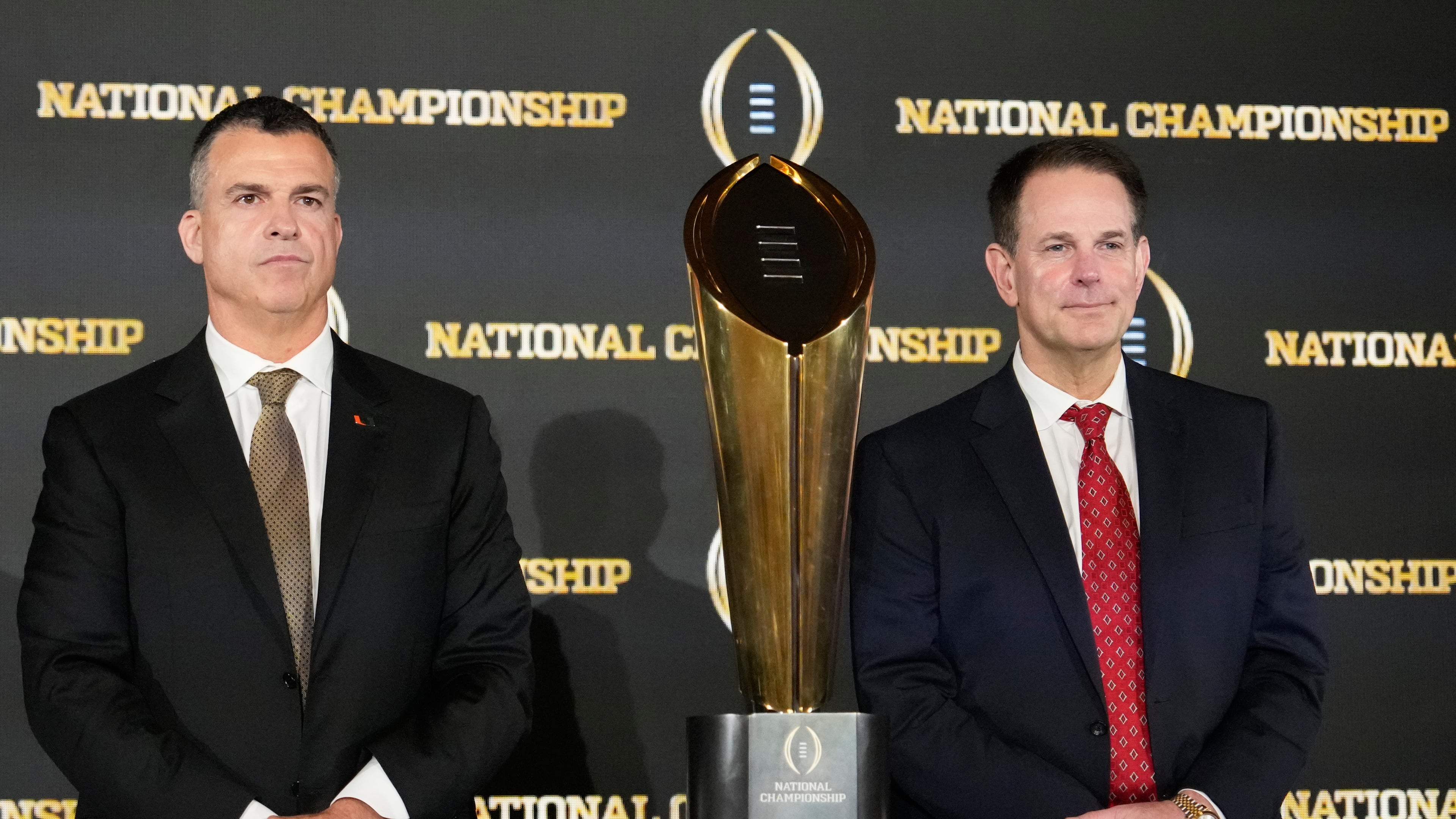 Miami head coach Mario Cristobal and Indiana head coach Curt Cignetti pose with the trophy after a news conference ahead of the College Football Playoff national championship game between Miami and Indiana, Sunday, Jan. 18, 2026, in Miami. The game will be played on Monday. (AP Photo/Chris Carlson)