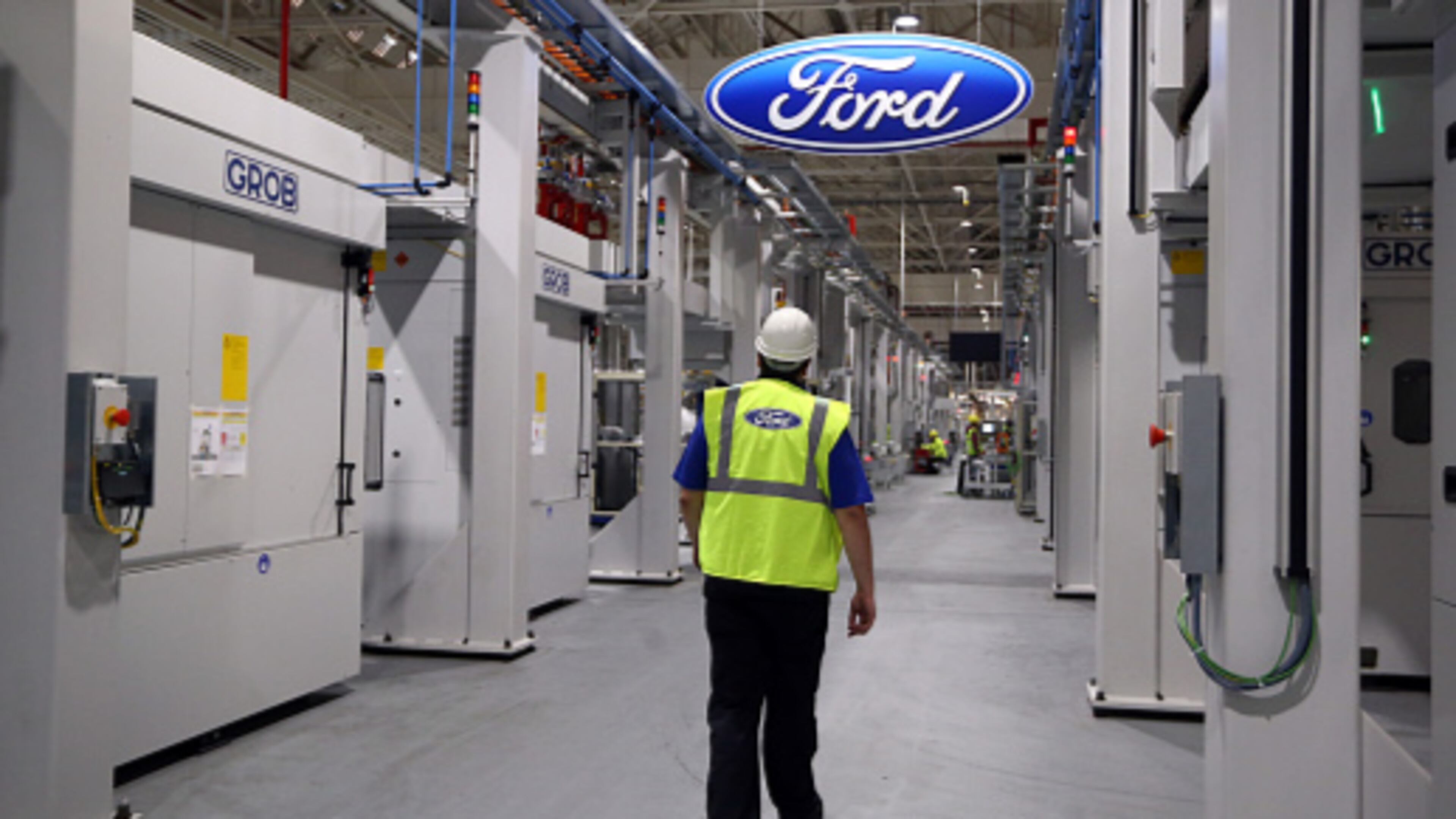 An employee walks past a Ford logo at the engine production line at a Ford factory in Dagenham, England. The majority of Ford’s 200,000 employees work in North America. A new report said the automaker is getting ready to chop 10 percent of its global workforce.