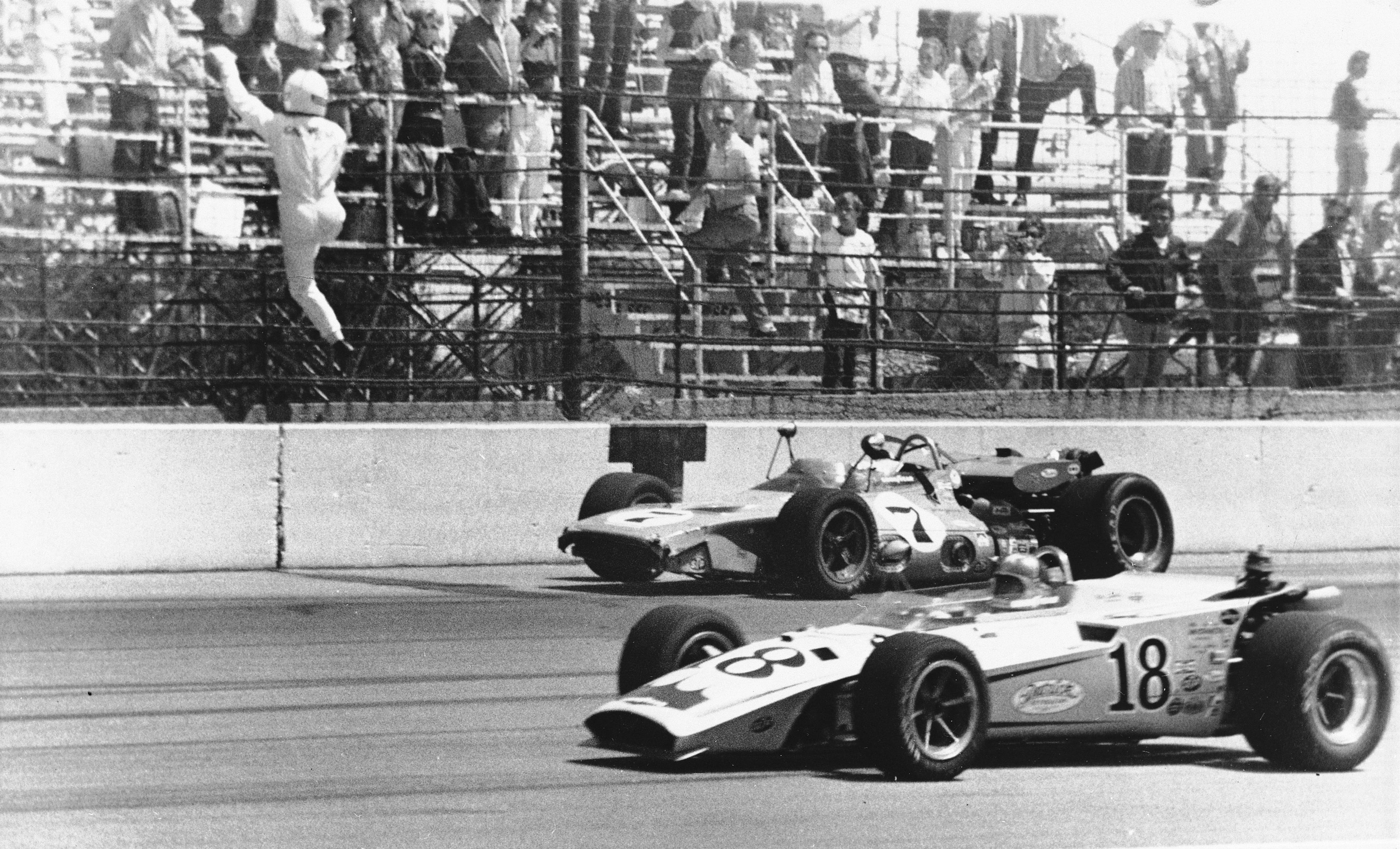 In this May 29, 1971 file photo, Gordon Johncock climbs a third turn fence after climbing from his wrecked racer after a multi-car wreck during the Indianapolis 500 auto race at Indianapolis Motor Speedway in Indianapolis, Ind. Johnny Rutherford (18) passes the wreckage in the foreground. (AP Photo/Gene Herrick, File)