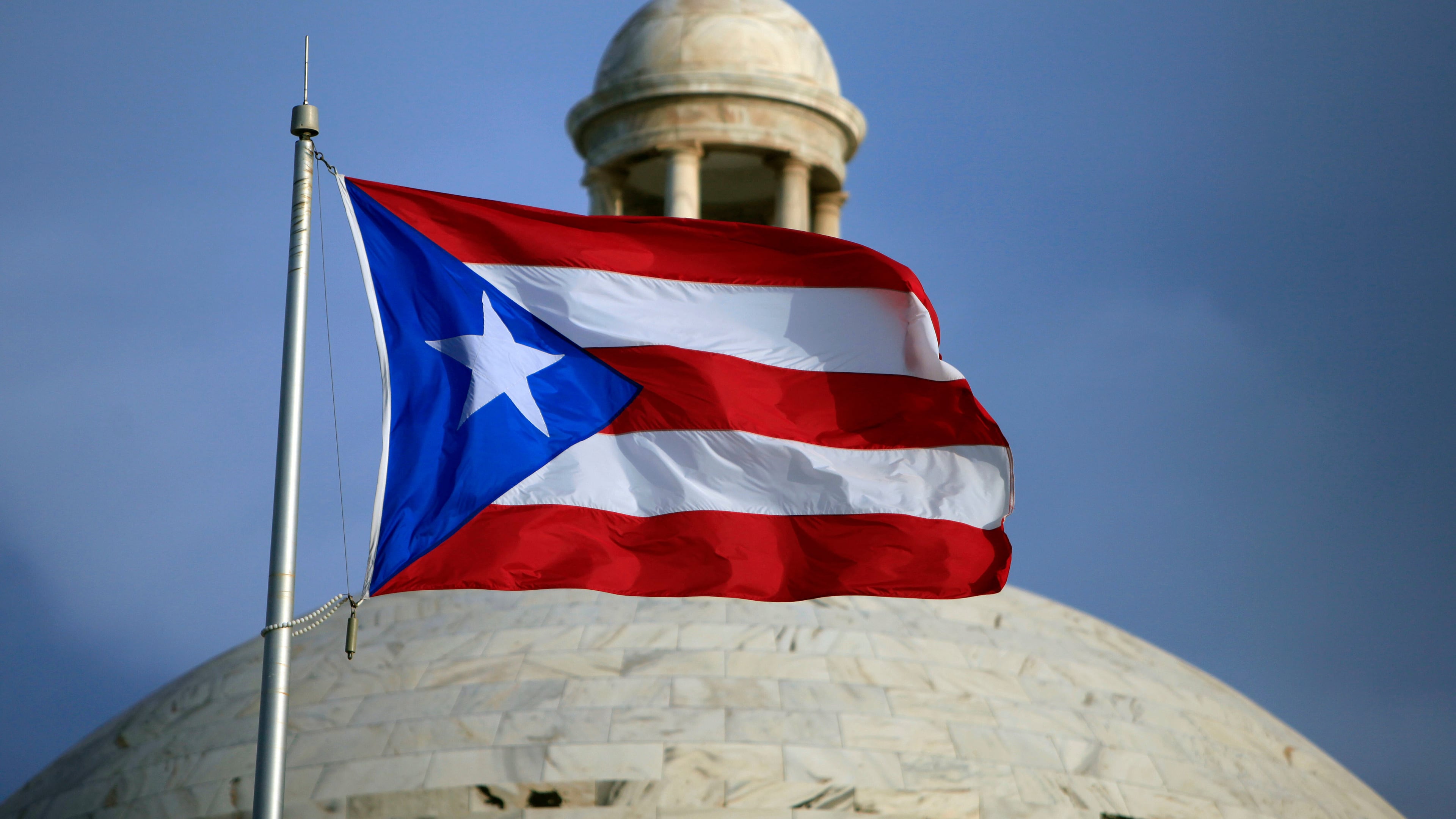 FILE - A Puerto Rican national flag flies in front of the Capitol building in San Juan, Puerto Rico, July 29, 2015. (AP Photo/Ricardo Arduengo, File)