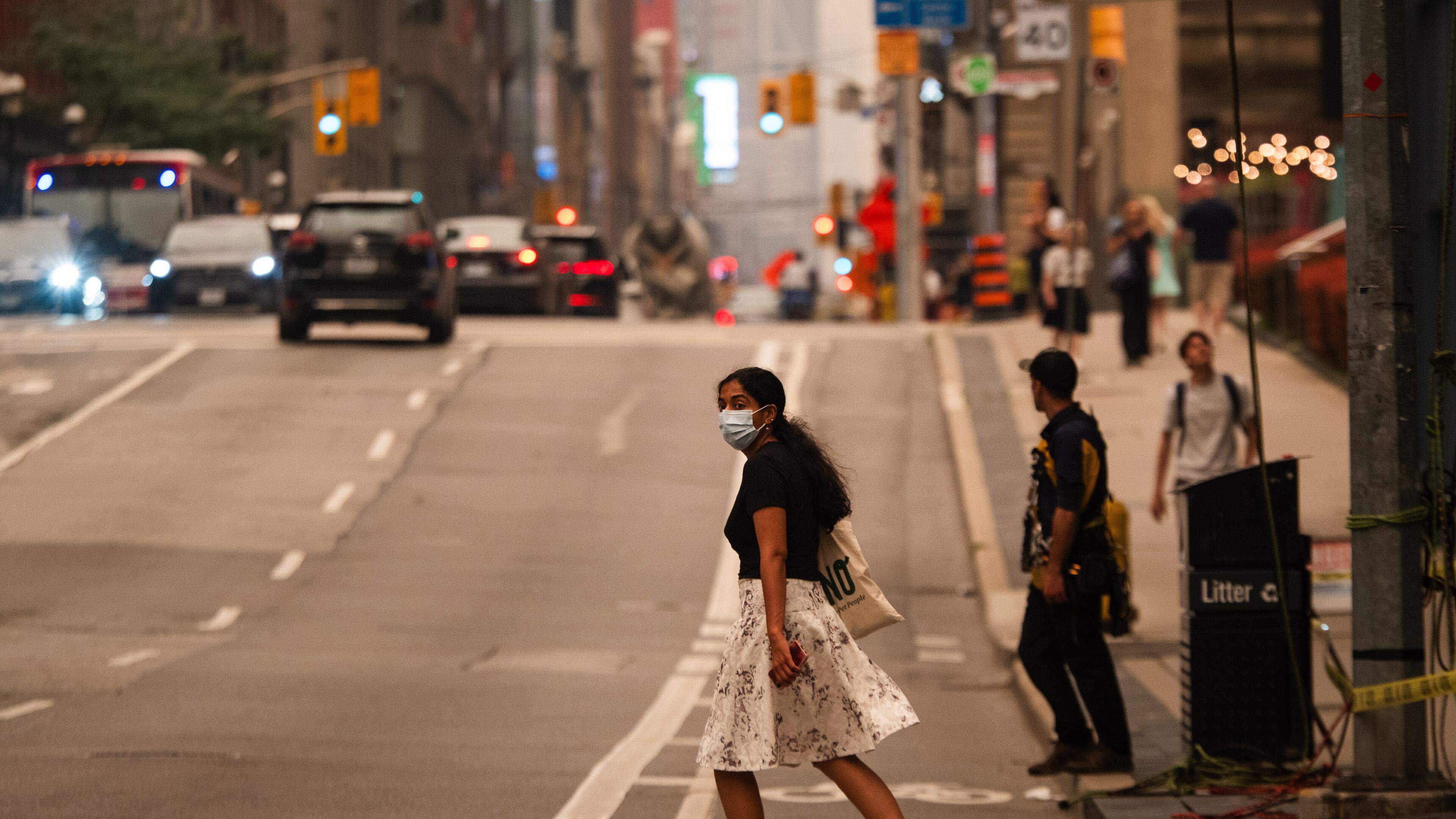 A woman wearing a mask crosses the street in Toronto as wildfire smoke fills the city, on Wednesday, July 15, 2026. (Laura Proctor/The Canadian Press via AP)