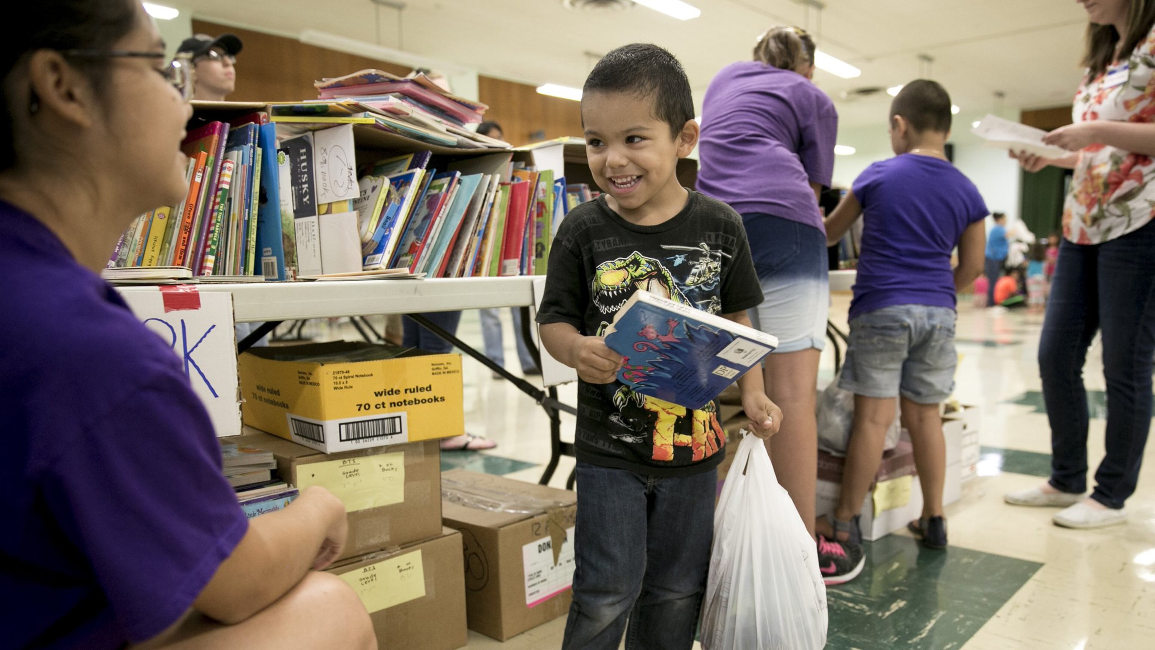 Elisabeth Torres-Schultz, 15, a volunteer with the nonprofit agency Manos de Cristo, gives a book to Diego Velazquez, 4, at Allan Elementary School in 2016. Manos de Cristo will give backpacks filled with school supplies and new clothes to 2,000 elementary school children while supplies last. JAY JANNER / AMERICAN-STATESMAN