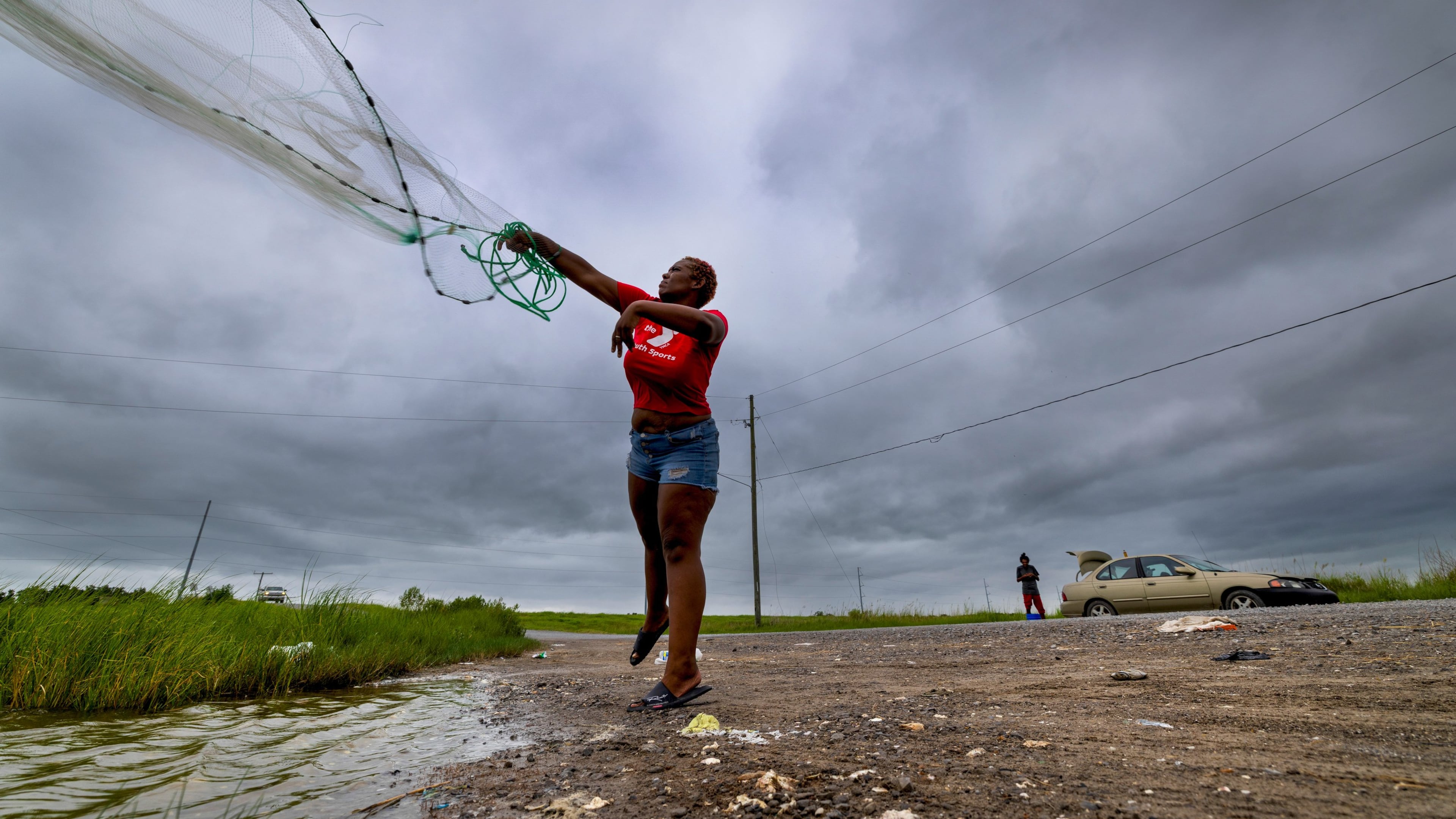 With skies darkening ahead of Tropical Storm Bertha, Latia Ancar practices her casting while she and a friend wait for the storm-driven tidal surge about 50 miles south of New Orleans on Wednesday, July 22, 2026, hoping it will bring more fish. (Chris Granger/The Times-Picayune/The New Orleans Advocate via AP)