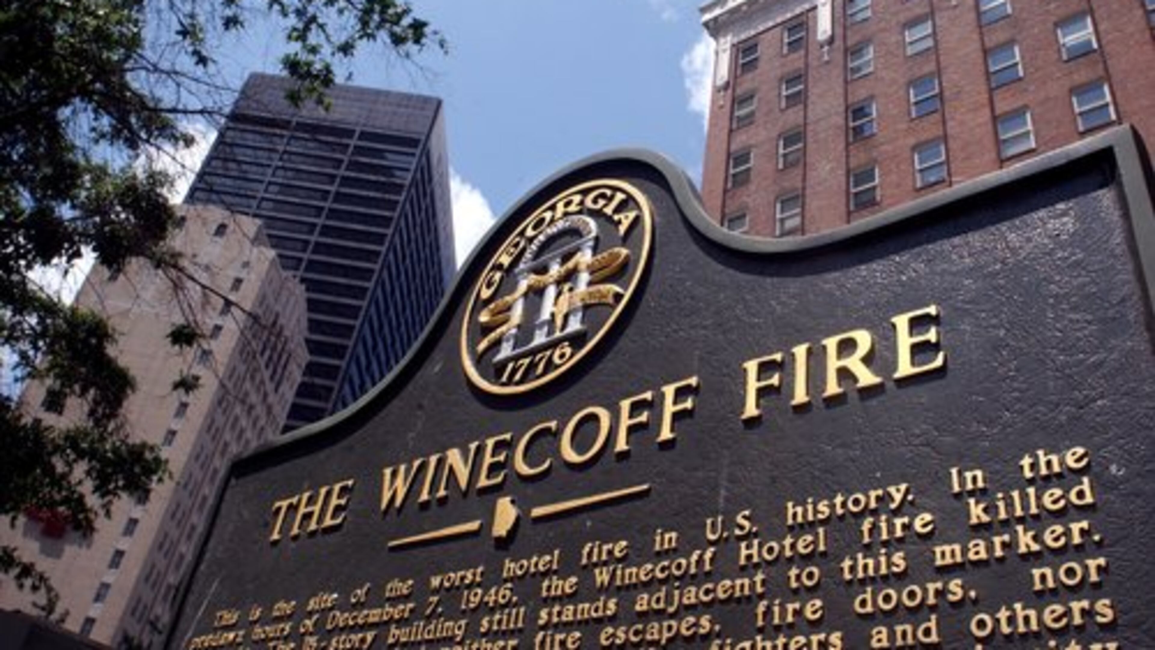 A historic marker stands in front of the old Winecoff Hotel (now the Ellis Hotel) with the Equitable Building soaring behind it on the left. The Winecoff burned on December 7, 1946, killing 119. It remains the country's worst hotel fire.