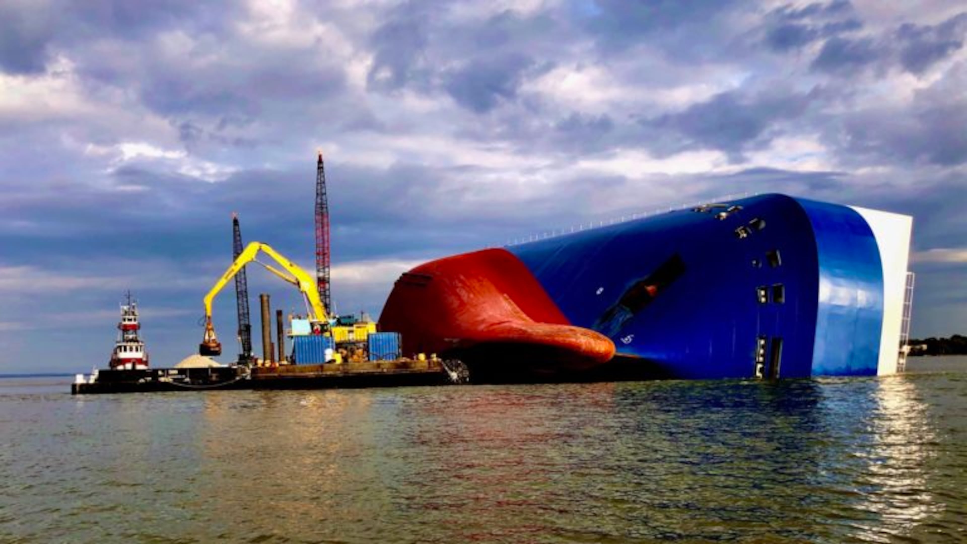 A knuckle boom excavator picks up 1-to-3-inch rock-aggregate from a container barge in St. Simons Sound, Georgia, Oct. 29, 2019. The excavator guided by sonar and GPS, strategically places the rock next to the hull of the Golden Ray to slow erosion.