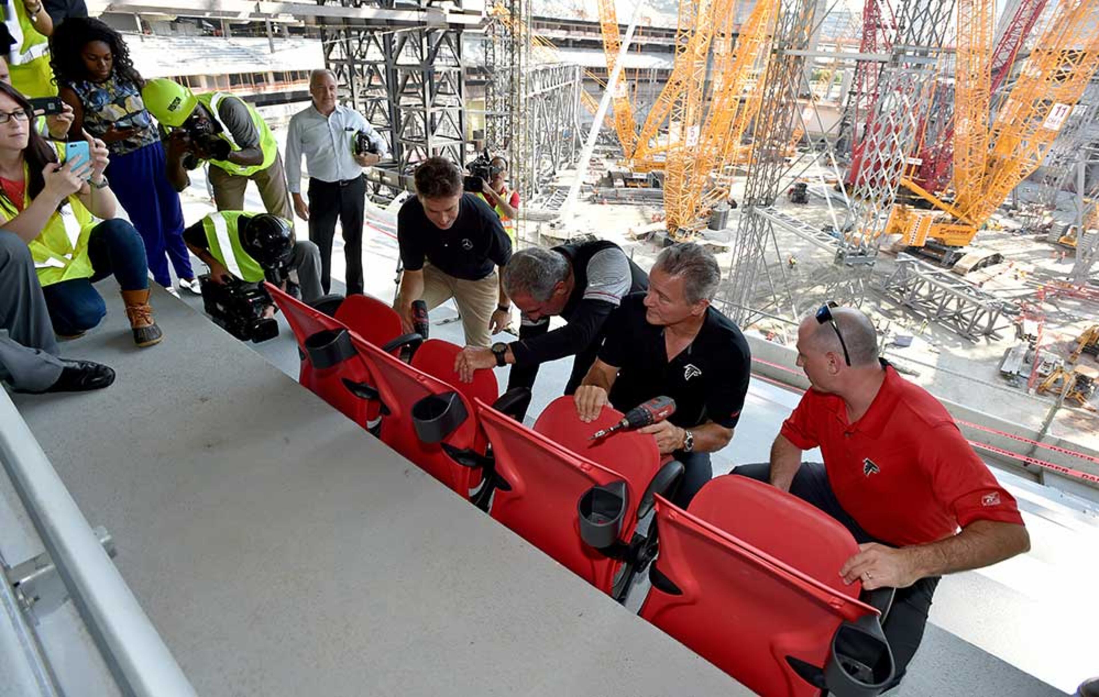 Dieter Exler, CEO of Mercedes-Benz USA, Arthur Blank, owner for the Atlanta Falcons, Steven Cannon and season ticket holder Stephen Klee install the first seats in Mercedes-Benz Stadium during a ceremony Thursday.