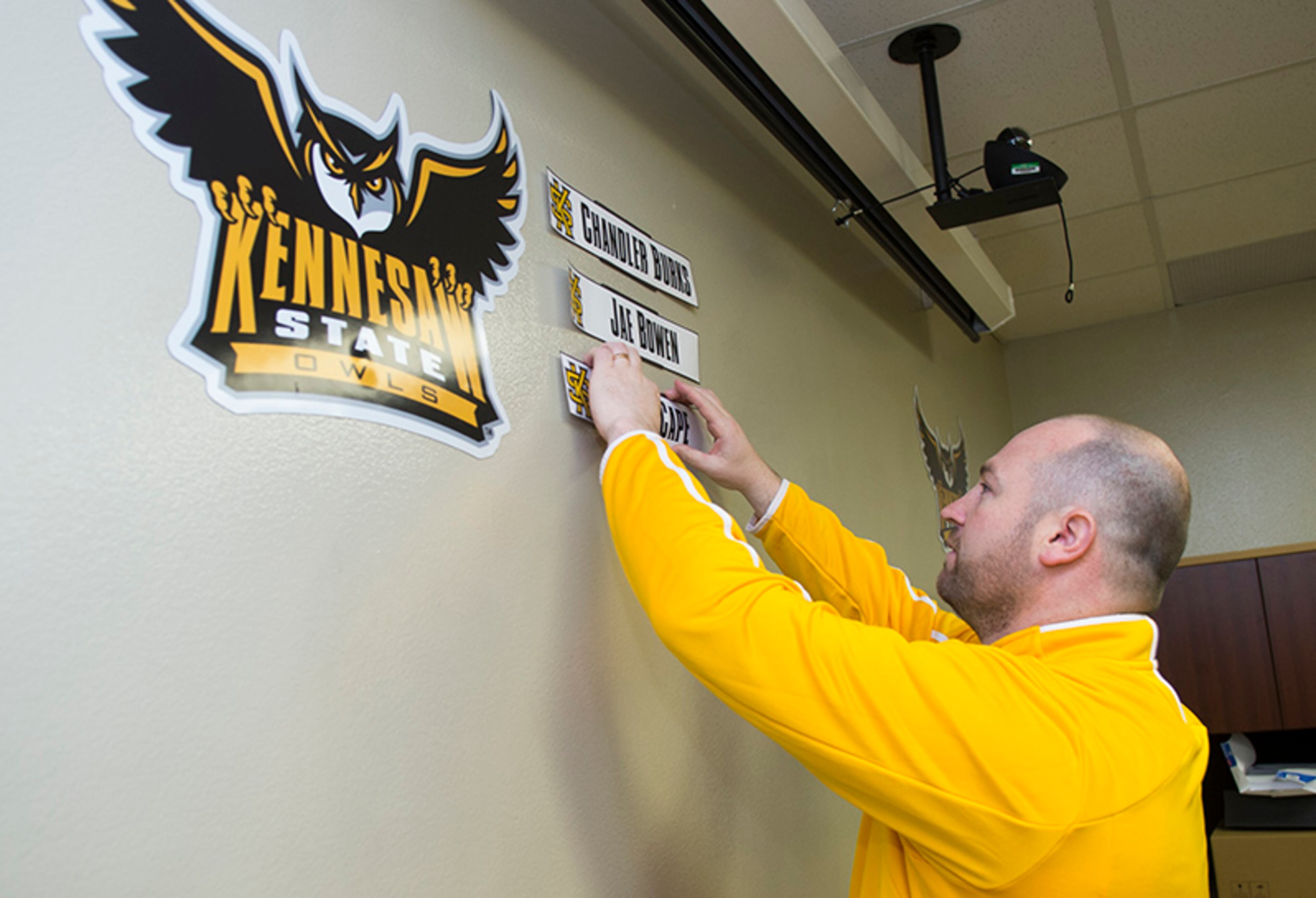 An Kennesaw State assistant places the names of signed recruits to its wall of signees. The Owls will play their first college football game in 2015.