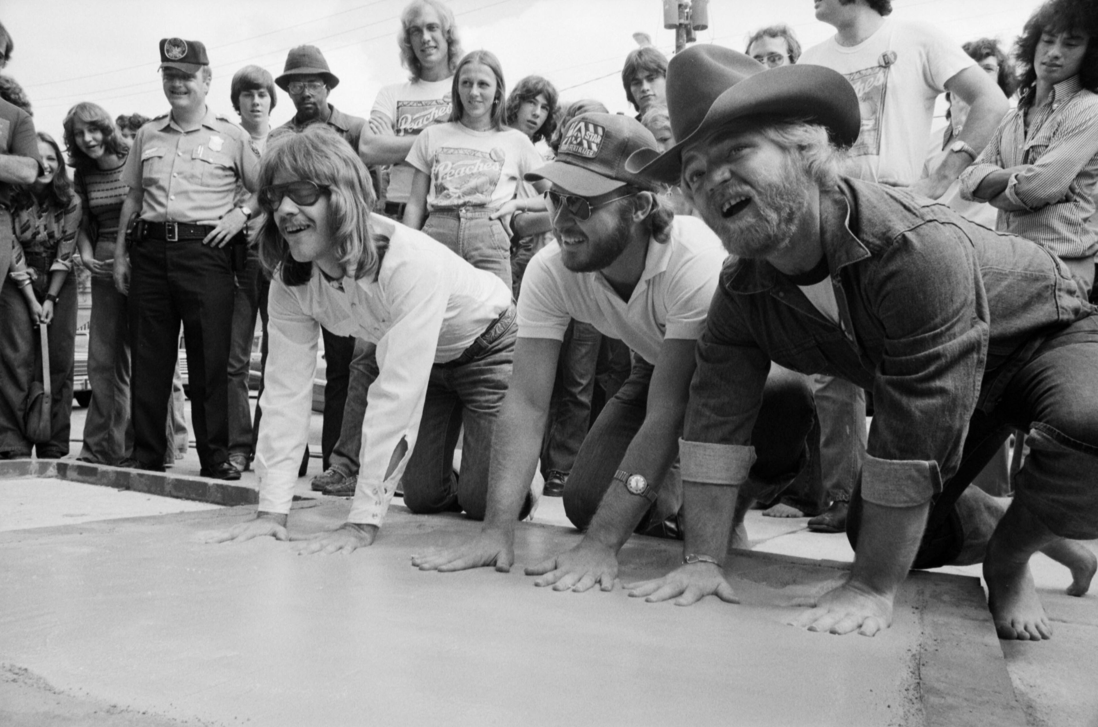 Members of the rock band ZZ Top pose while making their handprints in a cement block in front of Peaches Records and Tapes on Peachtree Street, September 1975. This ceremony became an Atlanta tradition similar in concept to the Hollywood Walk of Fame as artists visited the city while on tour and promoted their appearance.