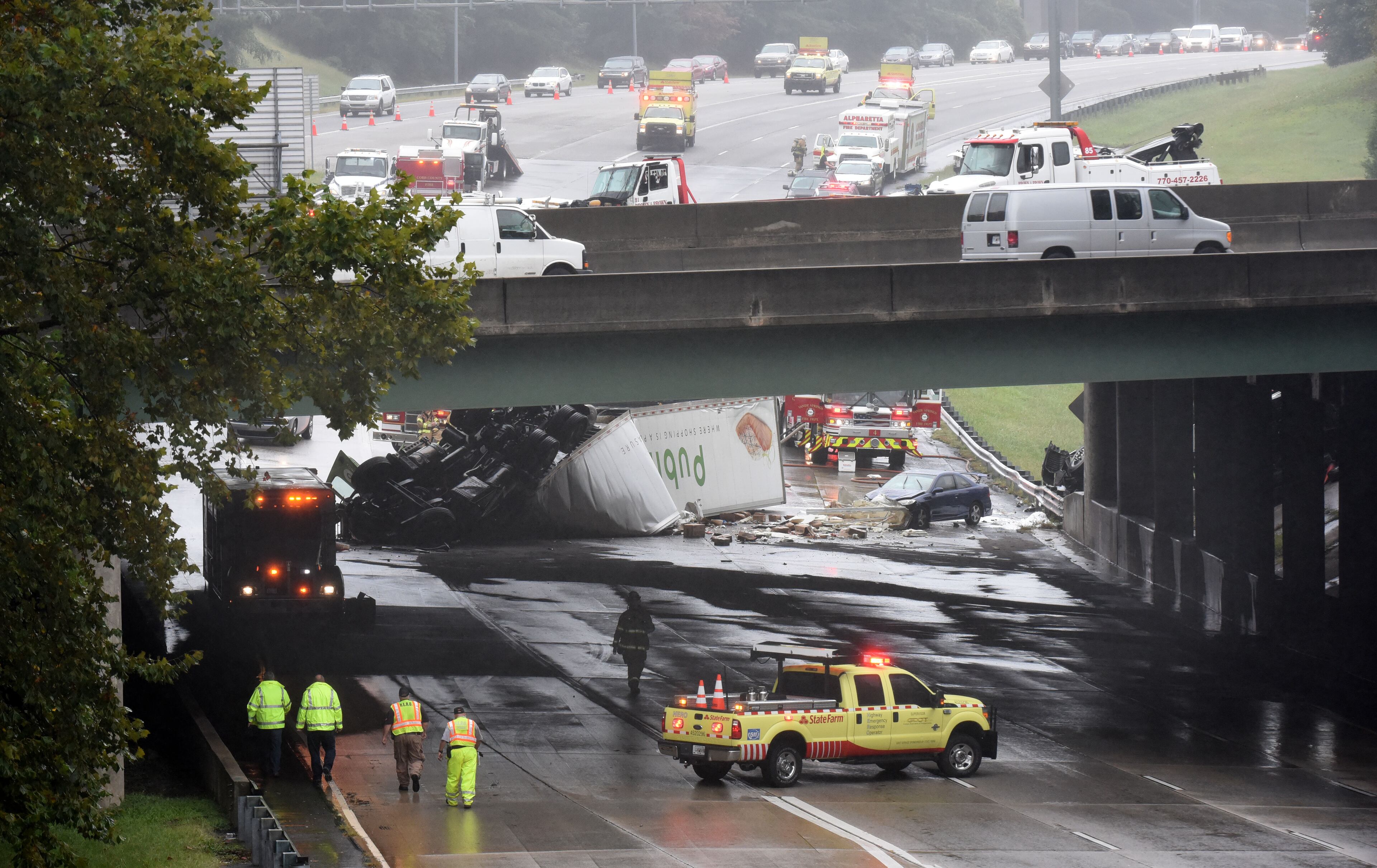 September 25, 2015 Sandy Spring - Authorities investigate at the scene where two tractor-trailers plunged off I-285 onto Ga. 400 on Friday, September 25, 2015. Two tractor-trailers plunged off I-285 onto Ga. 400, shutting down the busiest interchange in the state during the Friday afternoon lunch hour and sending three people to the hospital. All northbound lanes of Ga. 400 and some eastbound lanes of I-285 remained closed just before 2 p.m., and the Sandy Springs Police Department predicted the road closures would last through rush hour. HYOSUB SHIN / HSHIN@AJC.COM