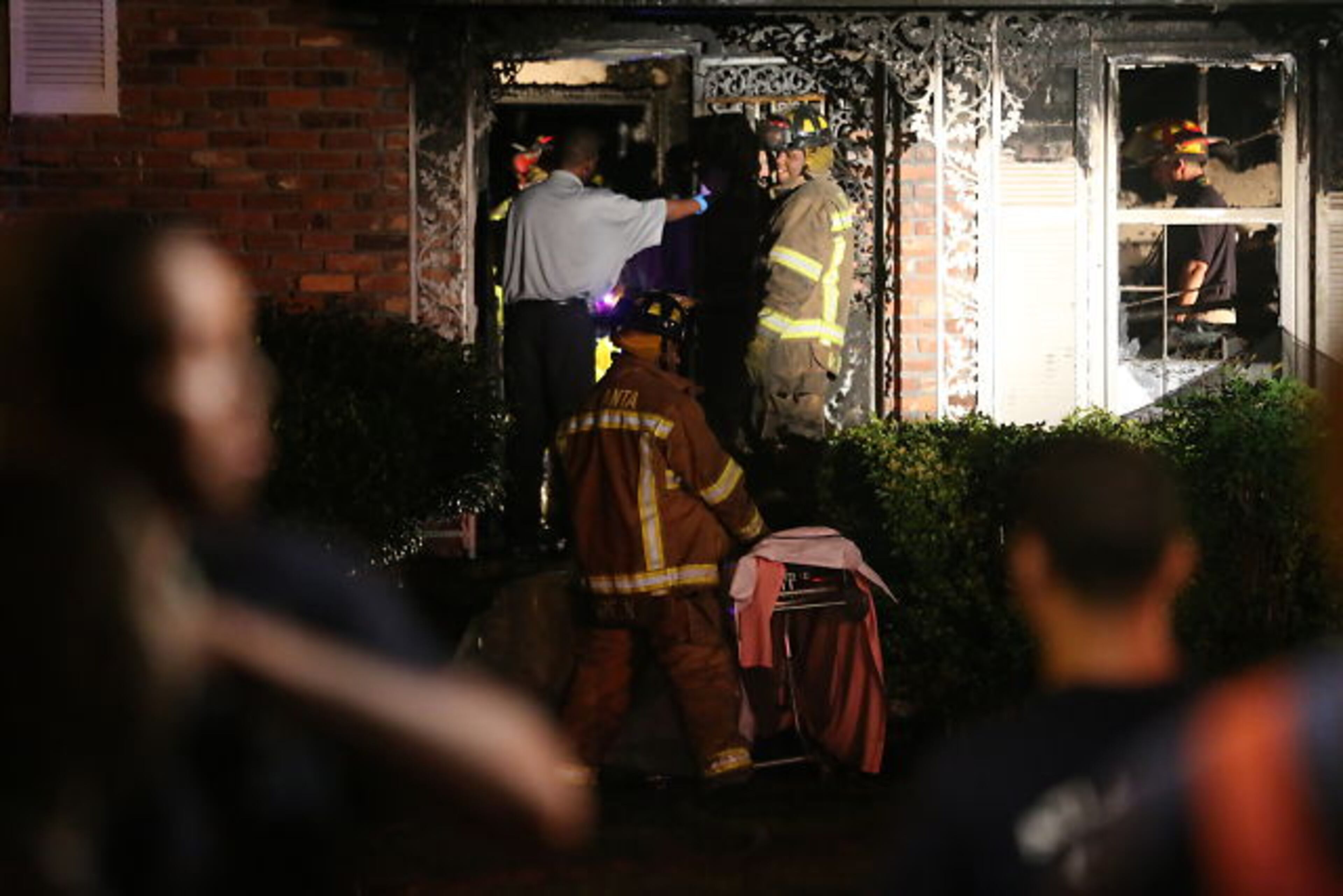 Firefighters enter a home on Revere Road in southwest Atlanta where three people died in a fire early Tuesday.