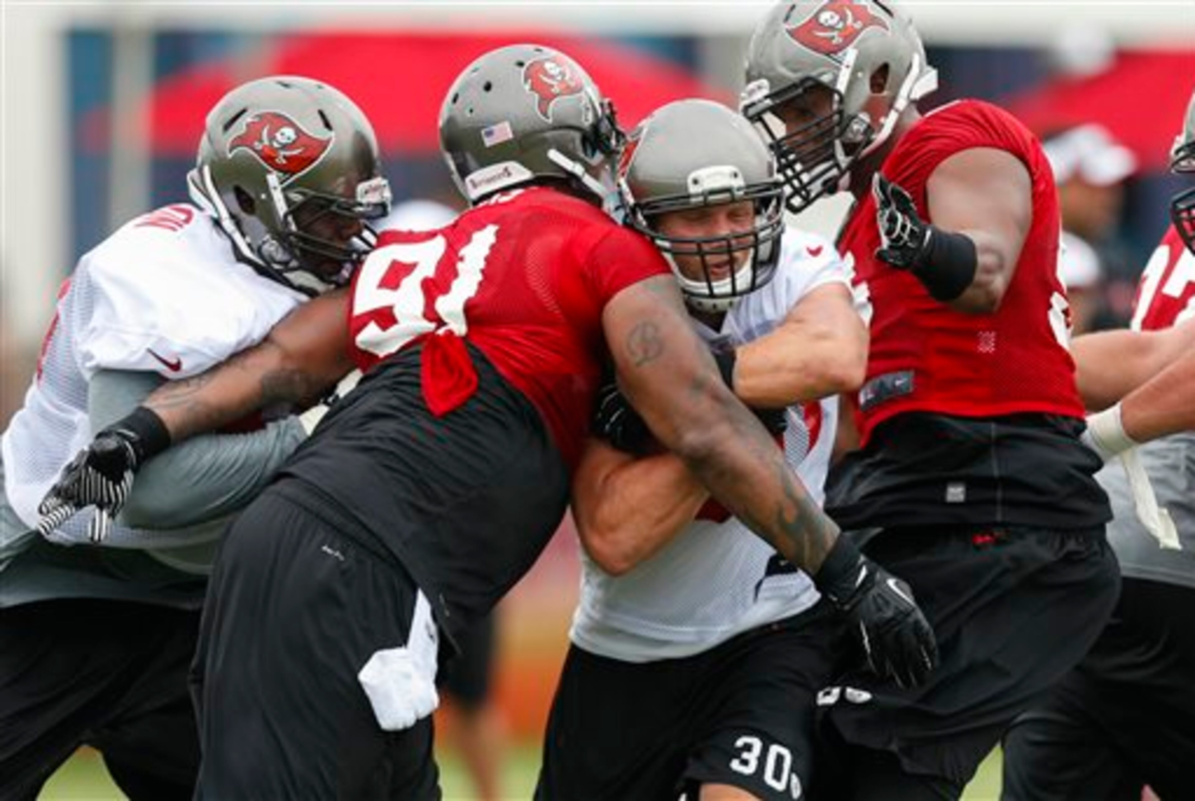 Tampa Bay Buccaneers running back Brian Leonard (30) squeezes through defenders Da'Quan Bowers (91) and Dekoda Watson with the help of a block from Demar Dotson, left, during NFL football training camp Thursday, July 25, 2013, in Tampa, Fla. (AP Photo/Mike Carlson)
