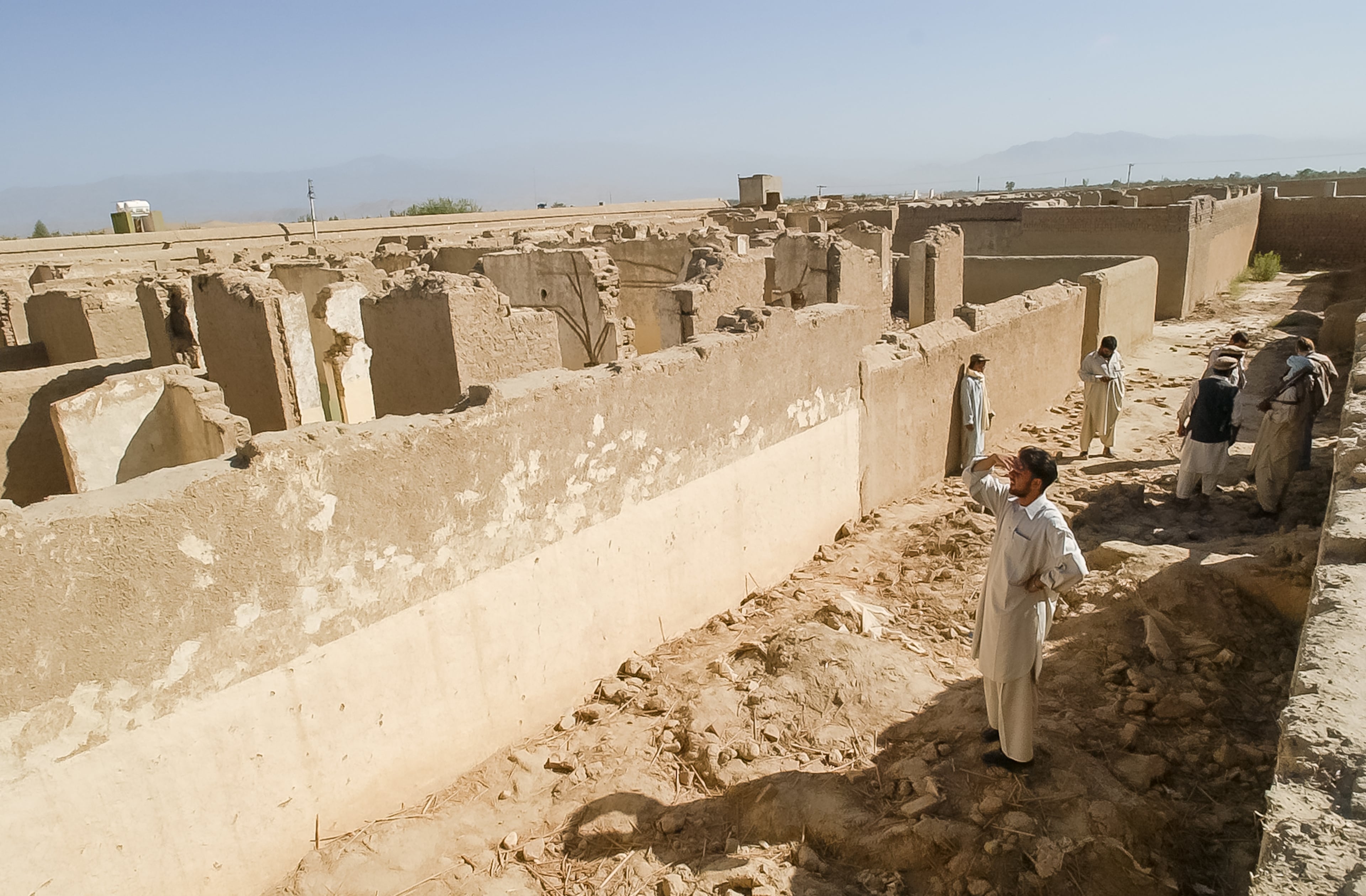 Near JALALABAD, AFGHANISTAN: Members of a local militia and visitors walk through the remains of Osama bin Laden's former residence compound outside Jalalabad, Afghanistan, Thursday, Sept. 5, 2002. (Bita Honarvar / The Atlanta Journal-Constitution)