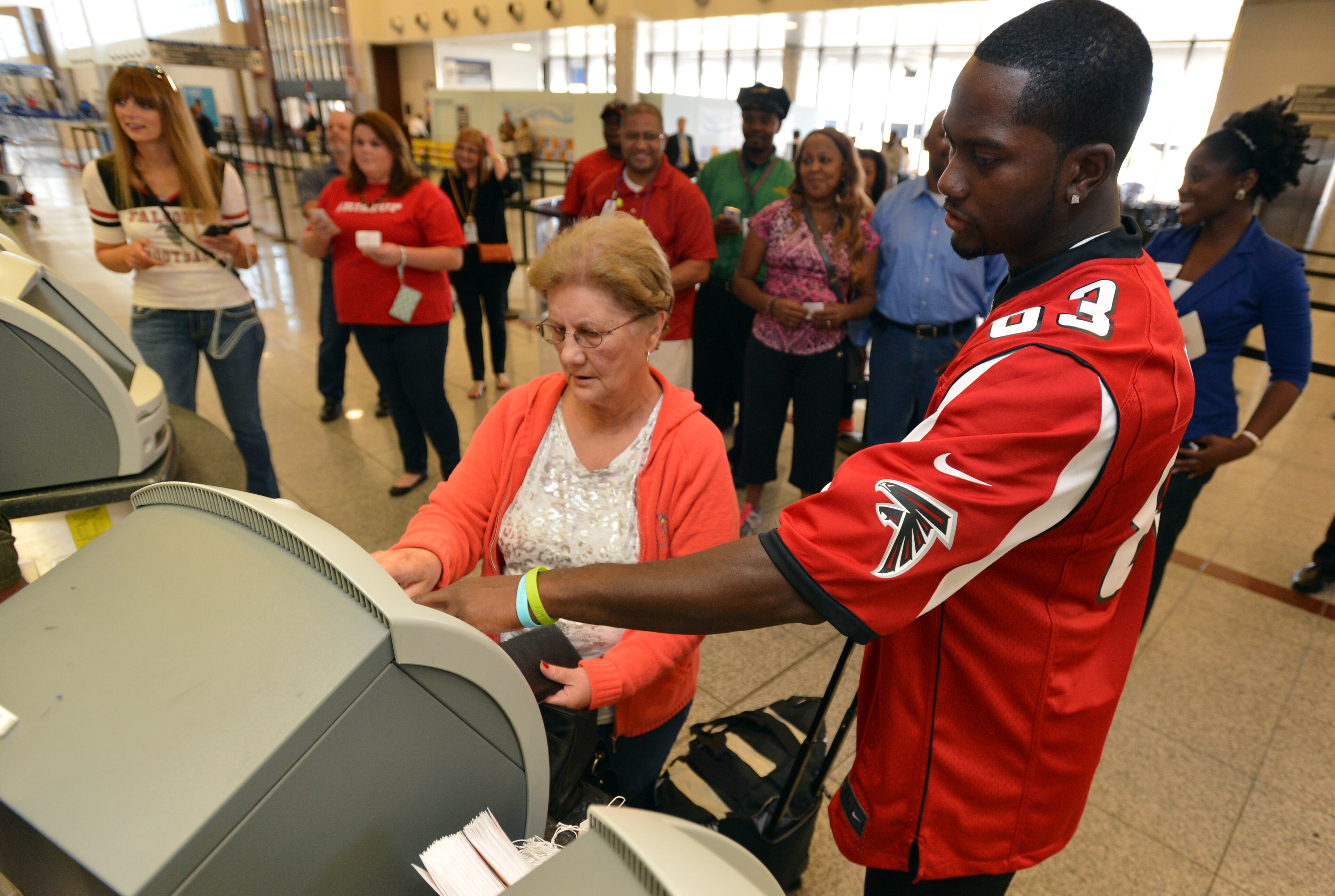 Atlanta Falcons wide receiver Harry Douglas helps Mary Joseph check in at the Southwest Airlines ticket counter. Five members of the Atlanta Falcons visited Southwest Airlines operations at Hartsfield-Jackson Atlanta International Airport with special guest Jordan Thomas. Thomas, 14, was diagnosed with cancer in 2012. As part of the Make-A-Wish Foundation, Thomas had the opportunity to hang out with members of the Falcons as they visited the Southwest ticket counter terminal, announced a flight departure and helped direct a plane away from the terminal. BRANT SANDERLIN /BSANDERLIN@AJC.COM