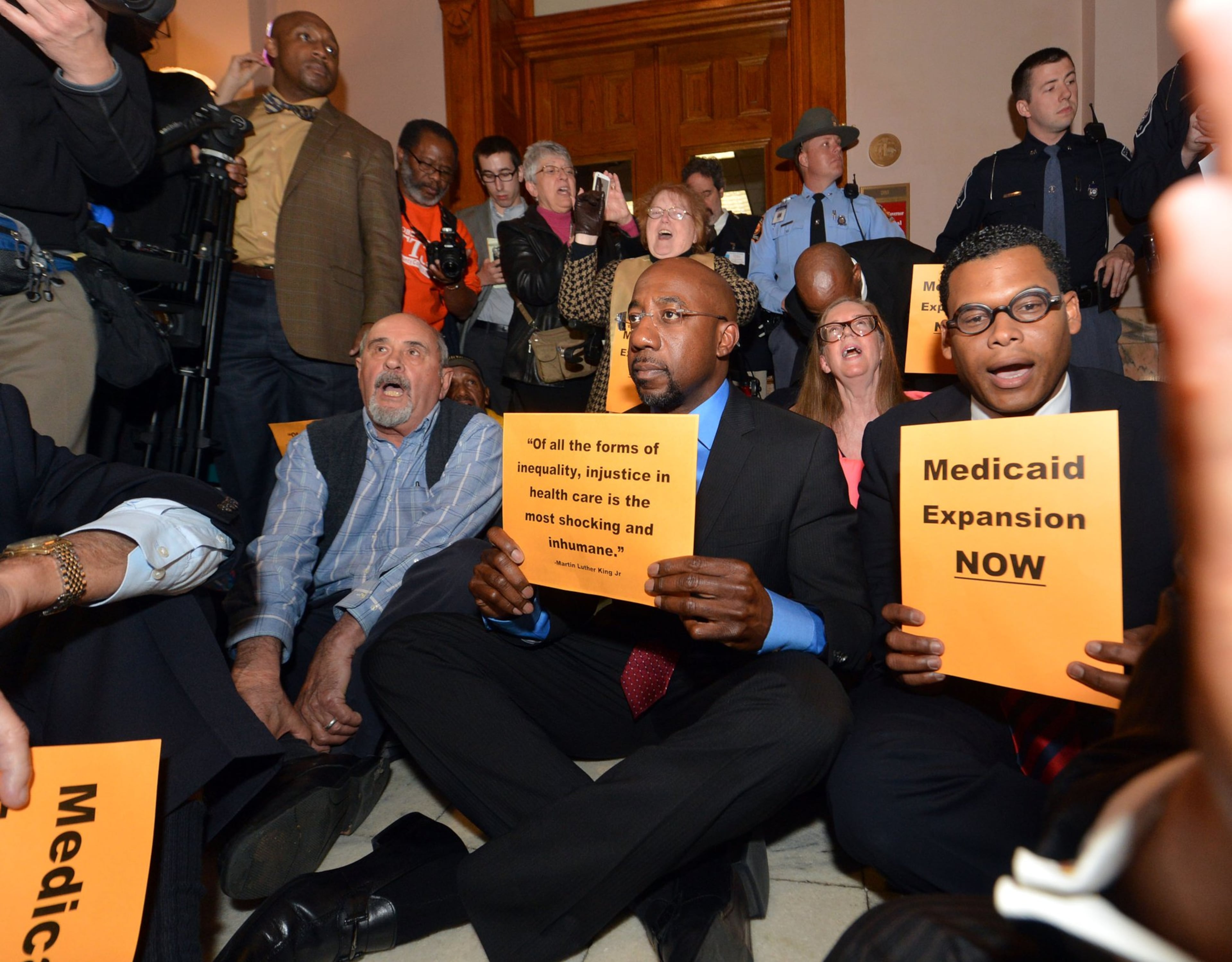 The Rev. Raphael Warnock (center), pastor of Ebenezer Baptist Church, was among protesters staging a sit-in in front of the Gov. Nathan Deal's office on Tuesday, March 18, 2014, calling for the governor to expand the state's Medicaid roster under the Affordable Care Act. They were arrested shortly afterward. (Kent D. Johnson/AJC 2014)