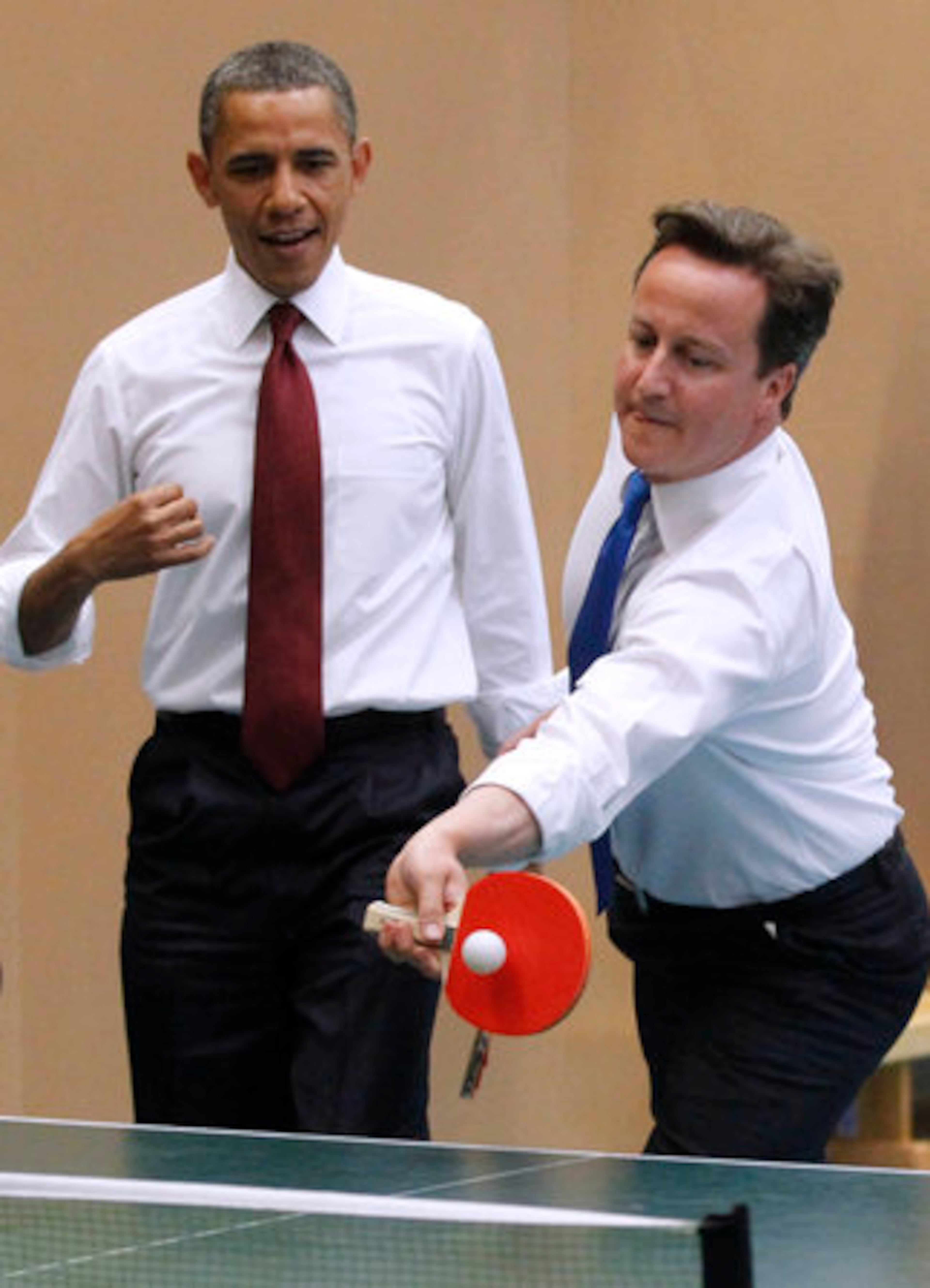 Obama watches as Cameron returns a shot.