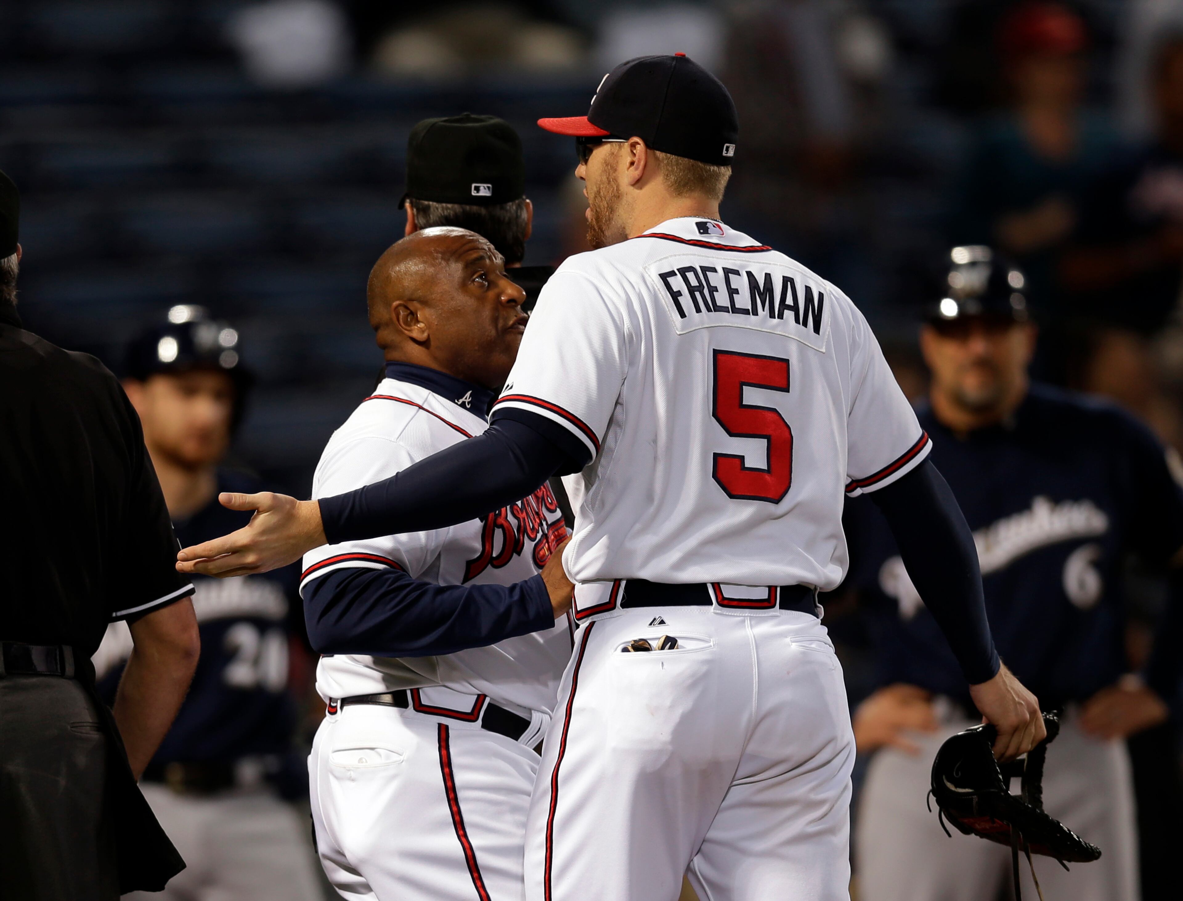 Atlanta Braves first baseman Freddie Freeman (5) is restrained by Atlanta Braves first base coach Terry Pendleton (9) during an argument with Milwaukee Brewers in the first inning of a baseball game Wednesday, Sept. 25, 2013 in Atlanta. (AP Photo/John Bazemore)