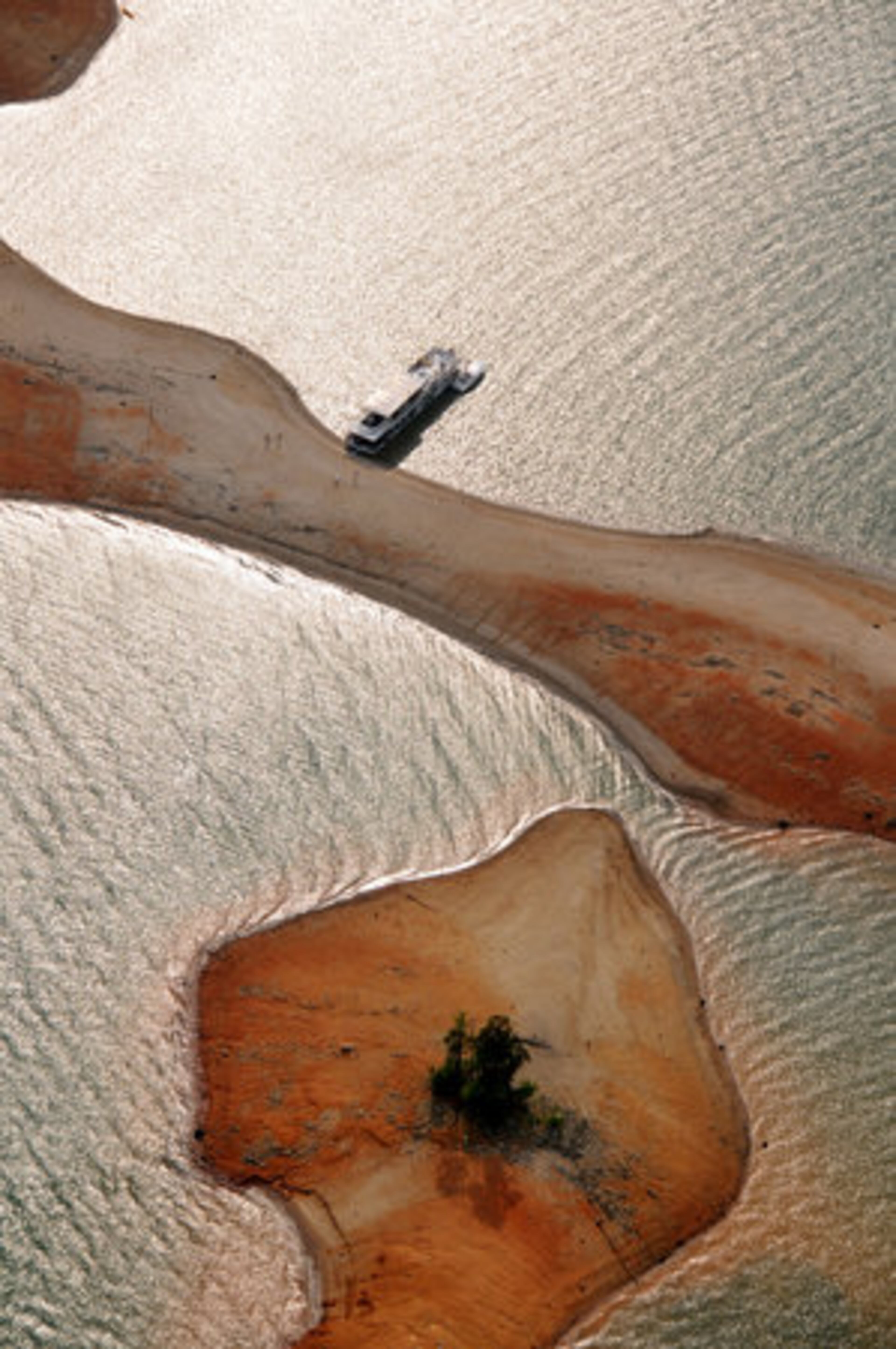 A large houseboat makes anchor, and passengers walk the sandy shoreline. Lake levels were at 1055.96 when this photo was taken, about 15 feet below full pool for this time of the year.