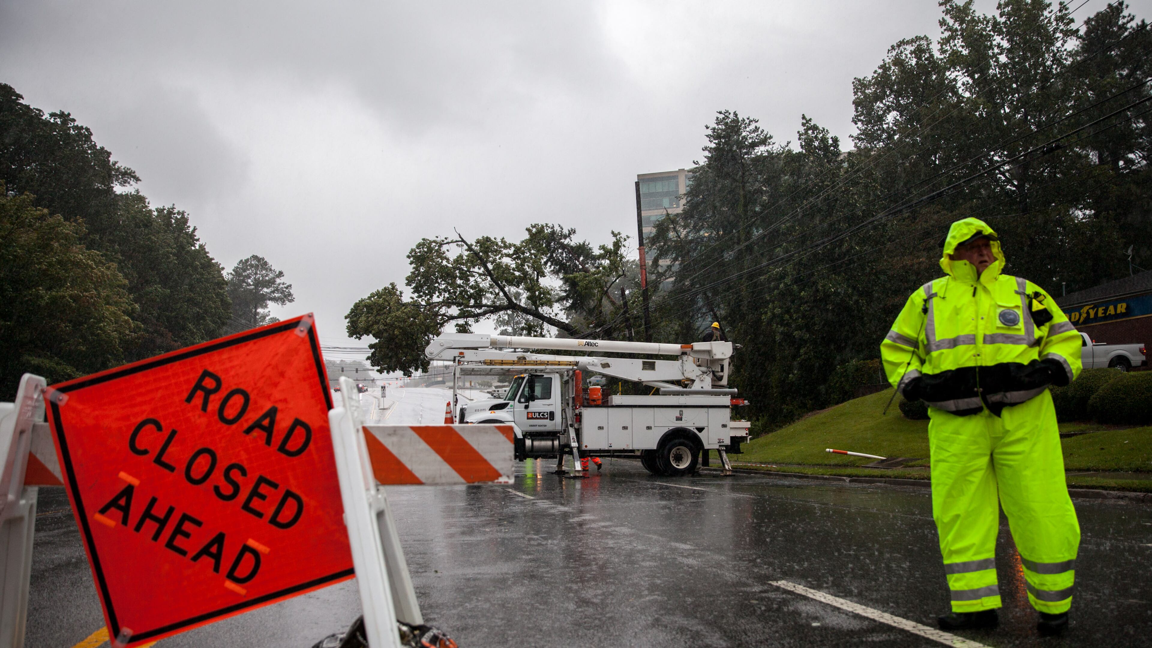An officer keeps watch as crews work to clear a tree that fell on power lines on Hammond Drive, Monday, Sept. 11, 2017, in Sandy Springs, Ga. BRANDEN CAMP/SPECIAL