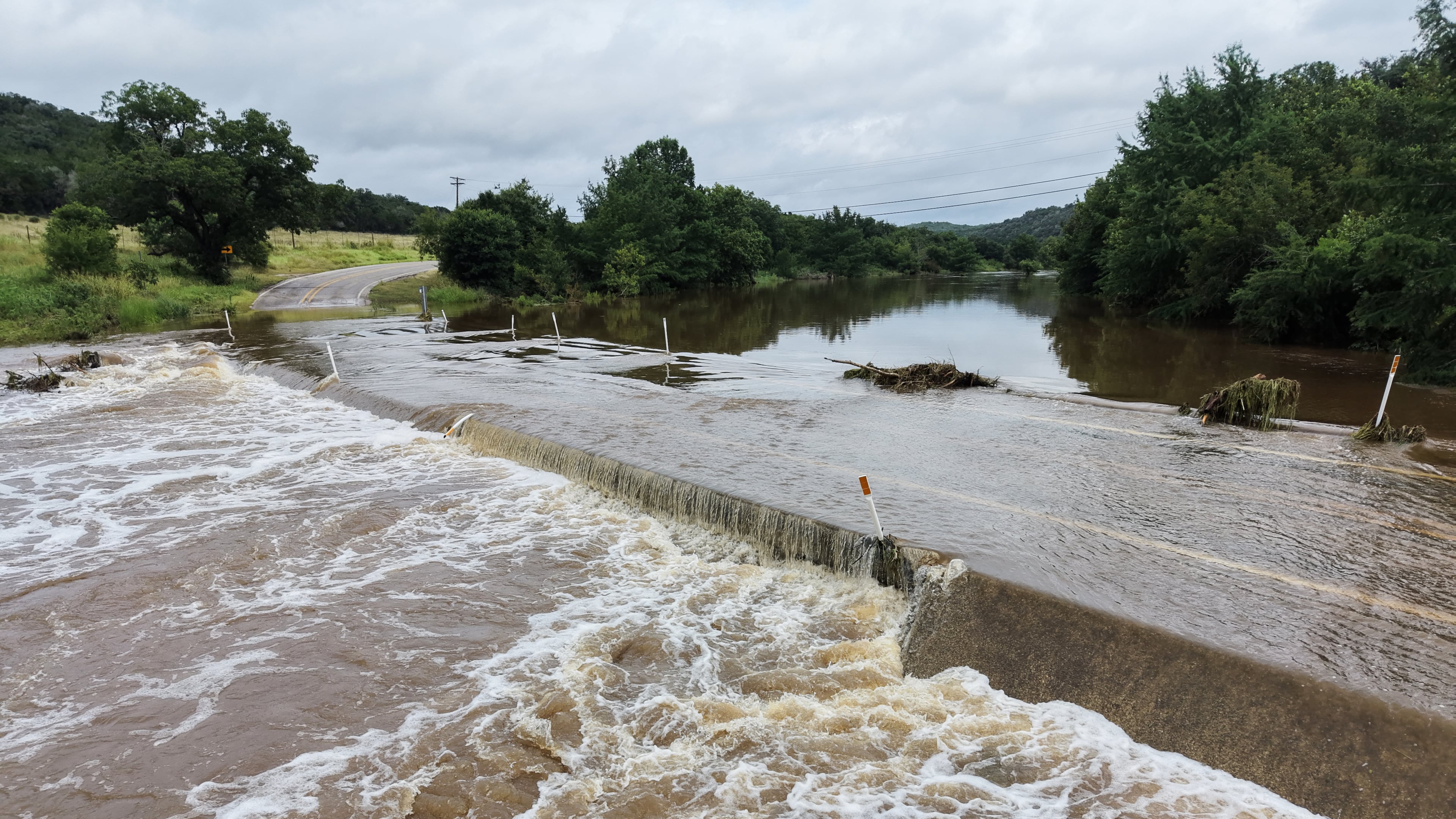 The Guadalupe River floods a crossing after a series of storms on Friday, July 17, 2026, in Hunt, Texas. (AP Photo/Gerald Herbert)