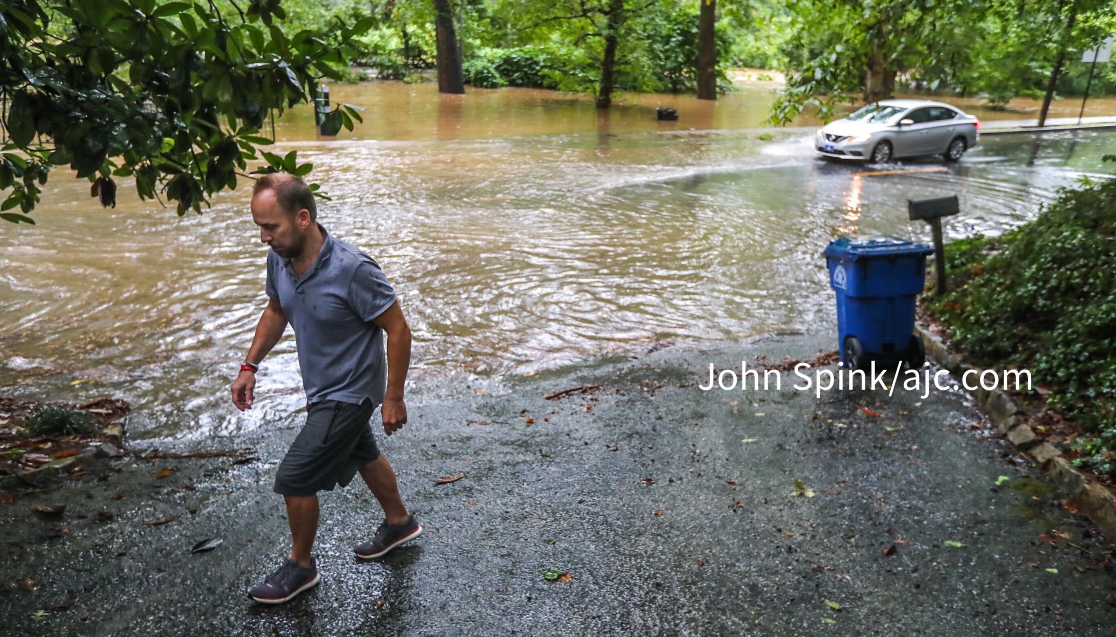 Peter Von Wismar puts out his recyclables on Peachtree Battle as Peachtree Creek rises over the road. The roadway had to be shut down at Woodward Way due to flooding.