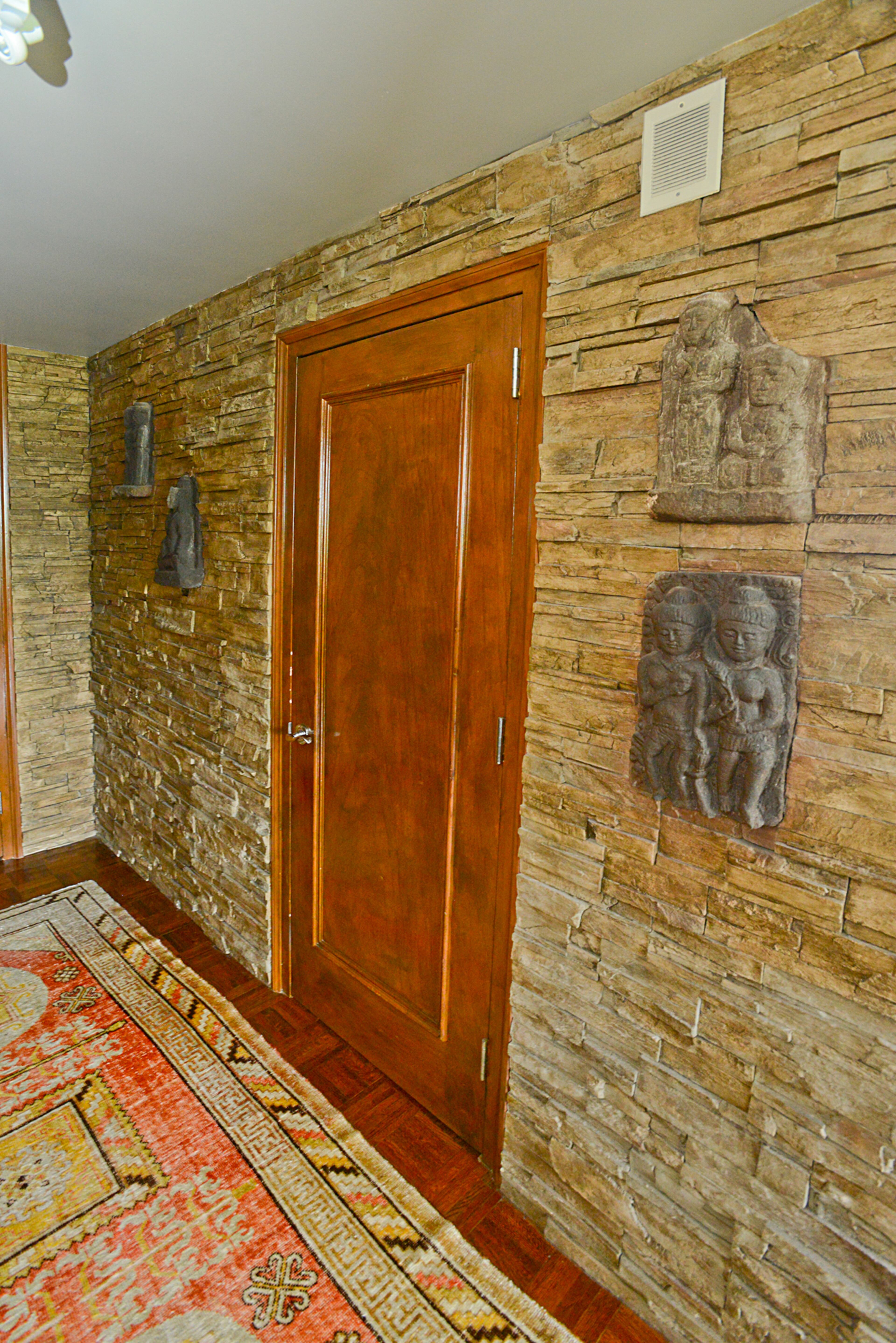 Stacked stone encapsulates the foyer of the condo in Atlanta's Plaza Towers, which was built in 1969. The sculptures and rug add to what homeowner Jason Moattar describes as the home's "mid-century modern with a tribal flair" design.
