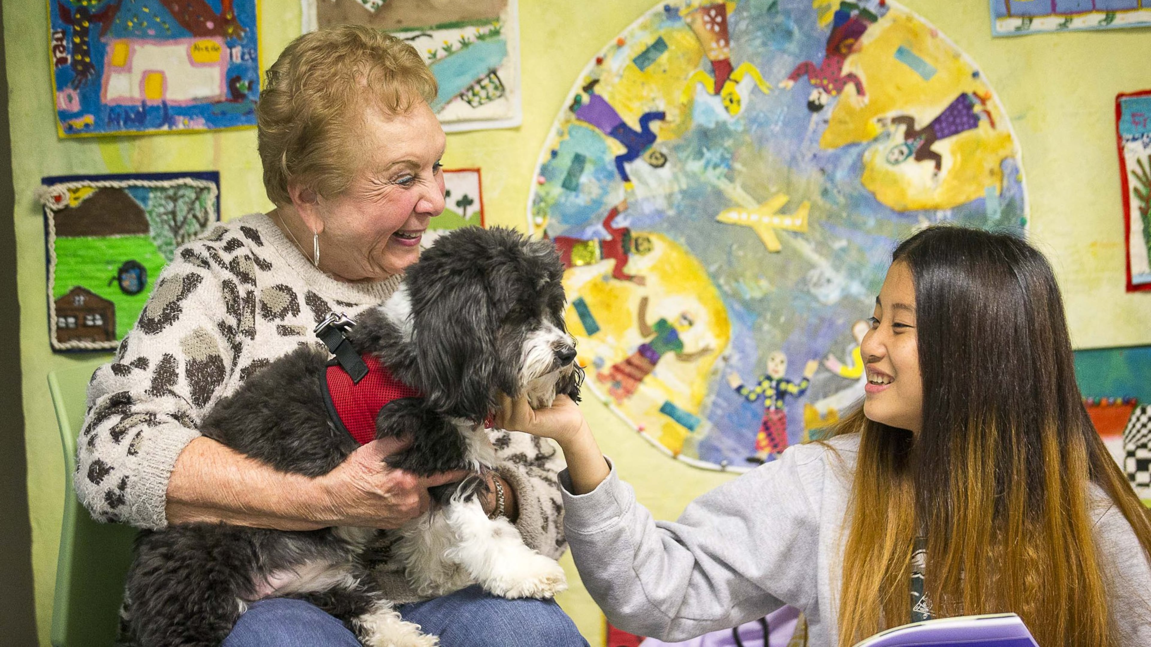 Cynthia Zeldin (left) allows Global Village Project student Mu Doe (right) to pet Lily, a registered therapy dog, during their reading time at the Global Village Project school in Decatur in November 2019. The Global Village Project is one of about 20 nonprofits to receive a grant from the Atlanta Women’s Foundation, as the organization announced the investment of $1.418 million to nonprofits providing programmatic support to women and girls in Metro Atlanta. (Alyssa Pointer/AJC)
