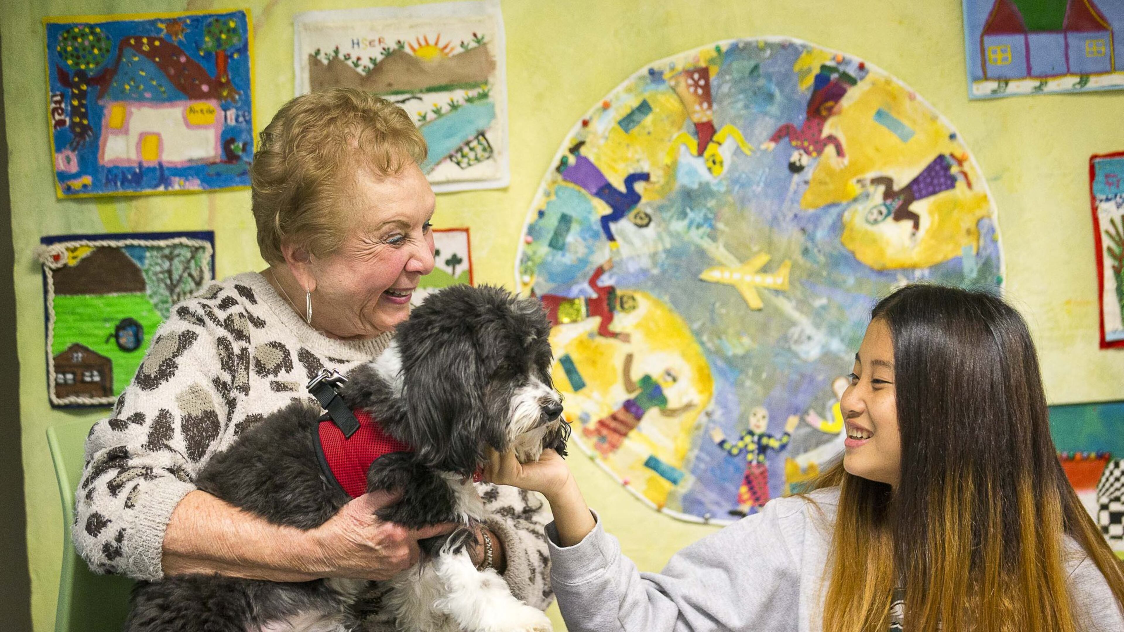 Cynthia Zeldin (left) allows Global Village project student Mu Doe (right) (last name withheld), 15, to pet Lily, a registered therapy dog, during their reading time at the Global Village Project school in Decatur. (ALYSSA POINTER/ALYSSA.POINTER@AJC.COM)