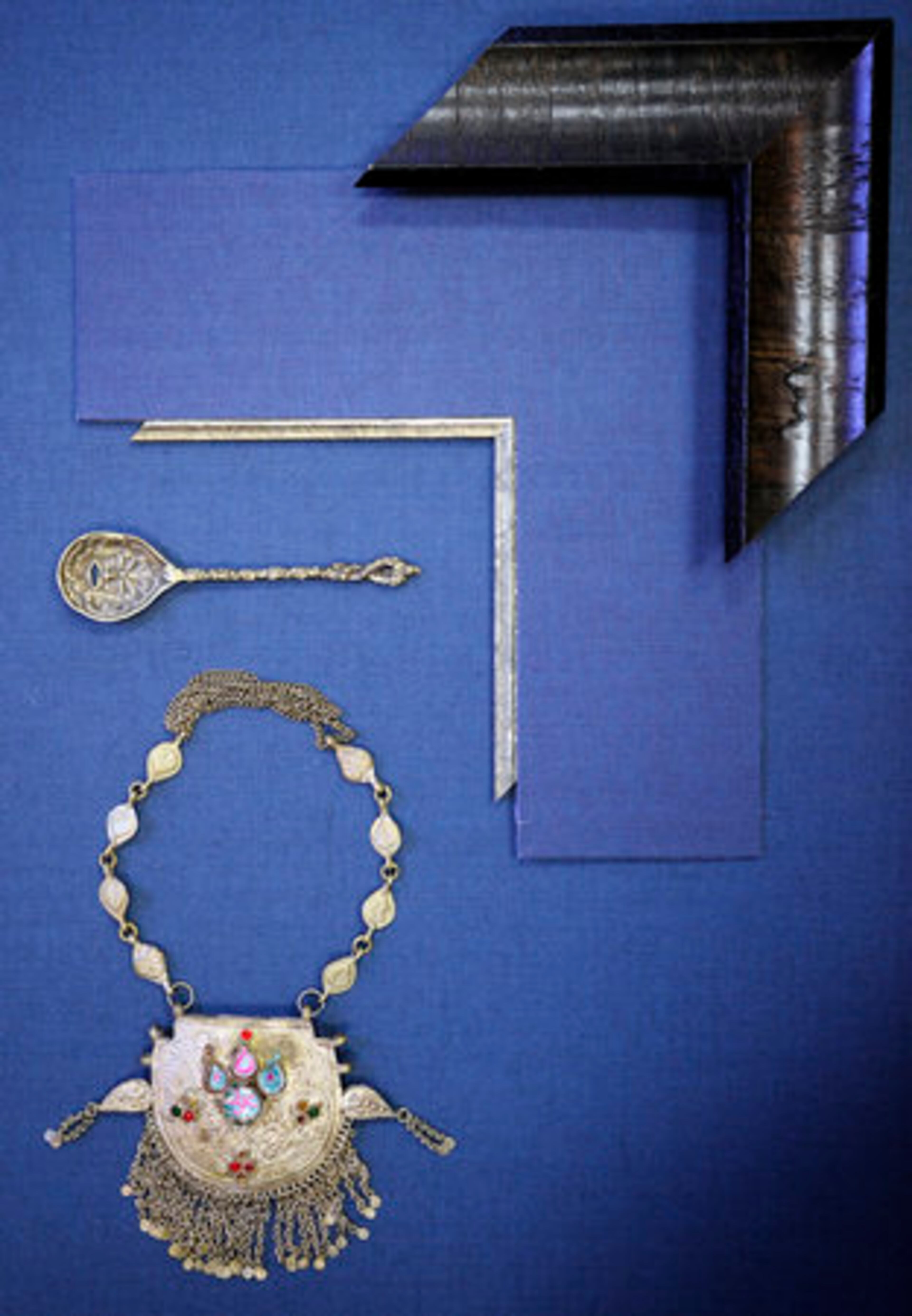 The metal shines when placed against smoky blue linen matting. The color choice also picks up the blue in the necklace's inlaid jewels.