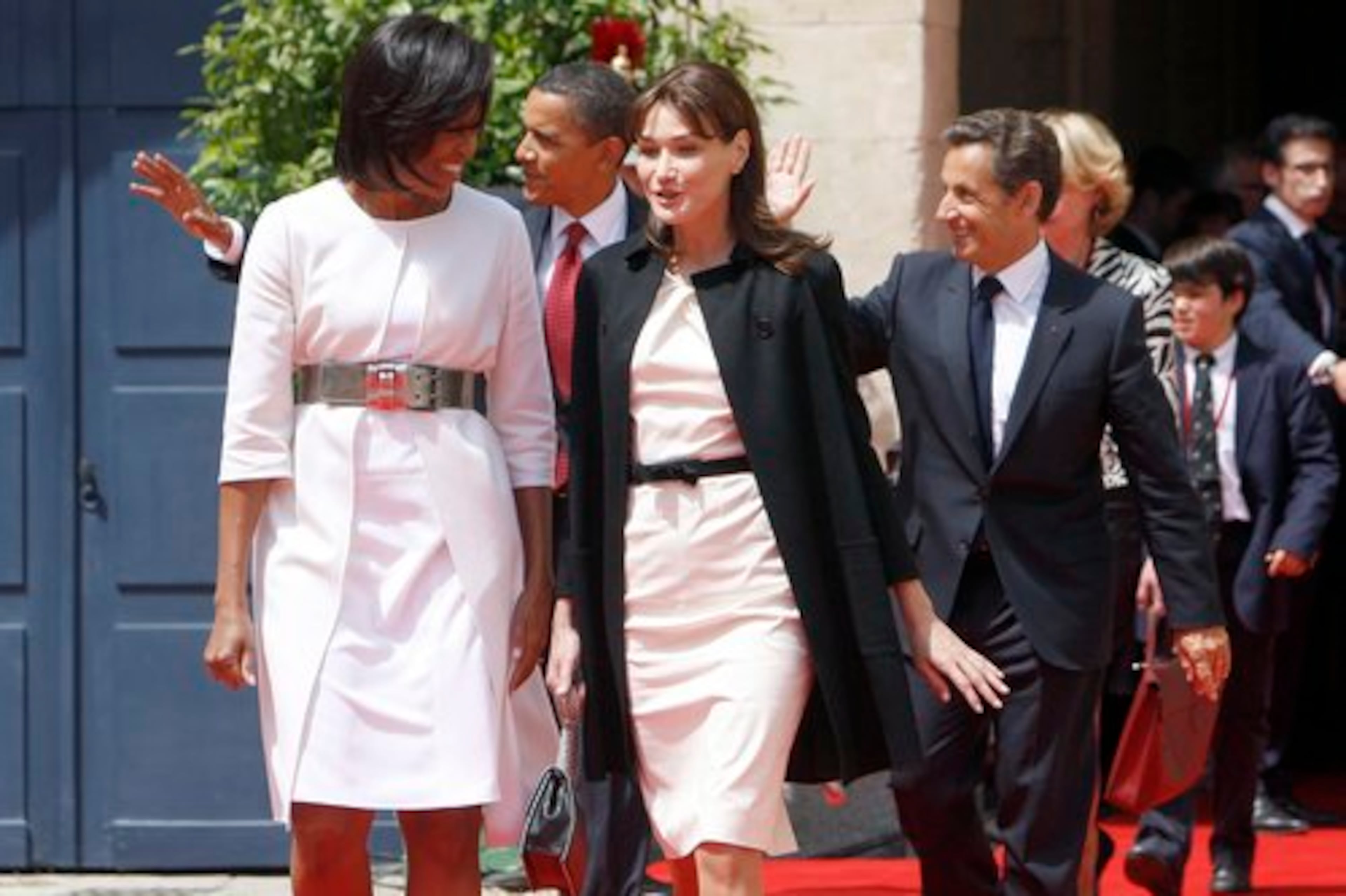 Michelle Obama and Carla Bruni-Sarkozy make small talk while their husbands wave.