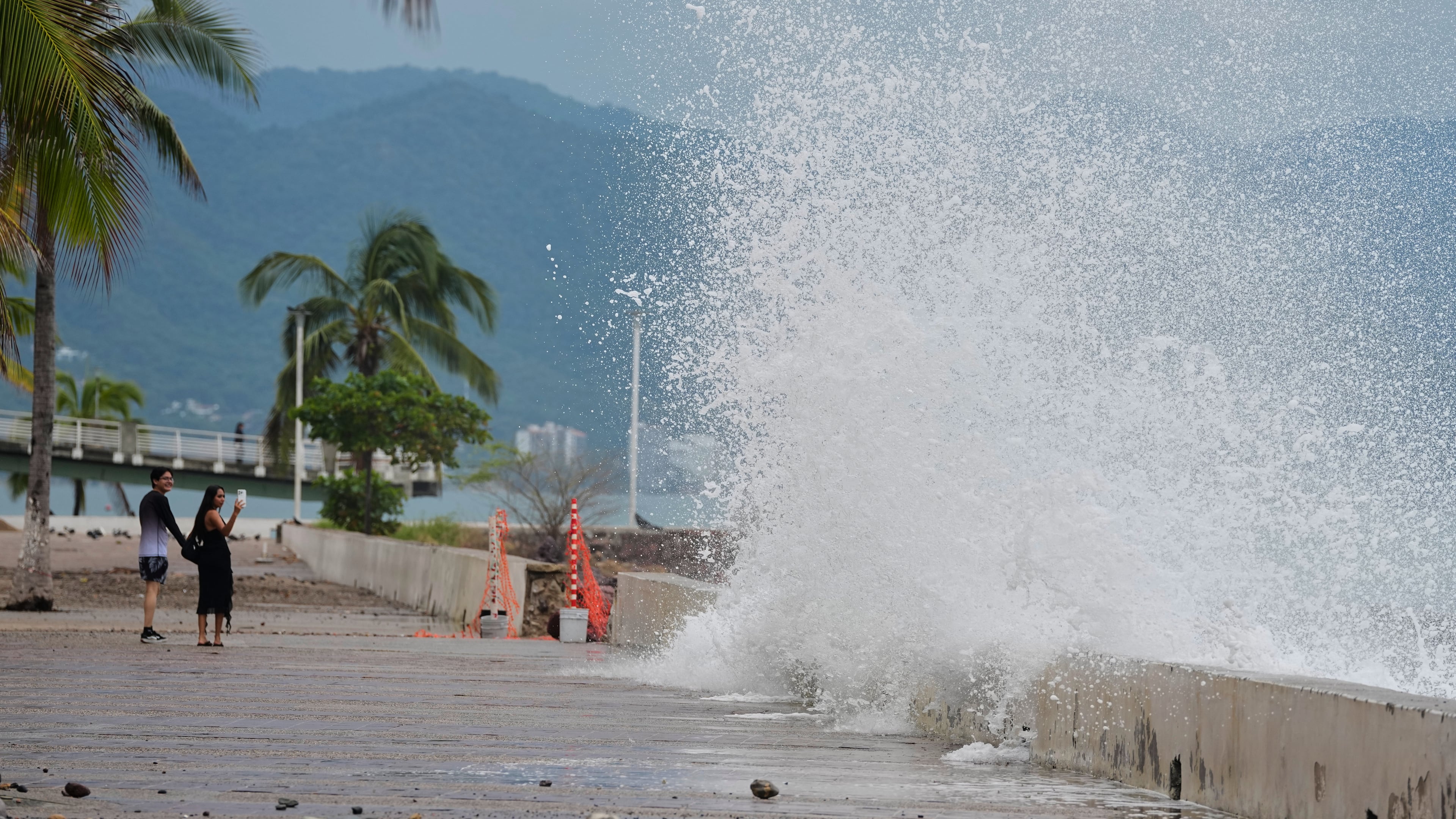 Tourists take photos of a water splashing against the wall as Hurricane Simon approaches Puerto Vallarta, Mexico, Sunday, Oct. 11, 2026. (AP Photo/Fernando Llano)