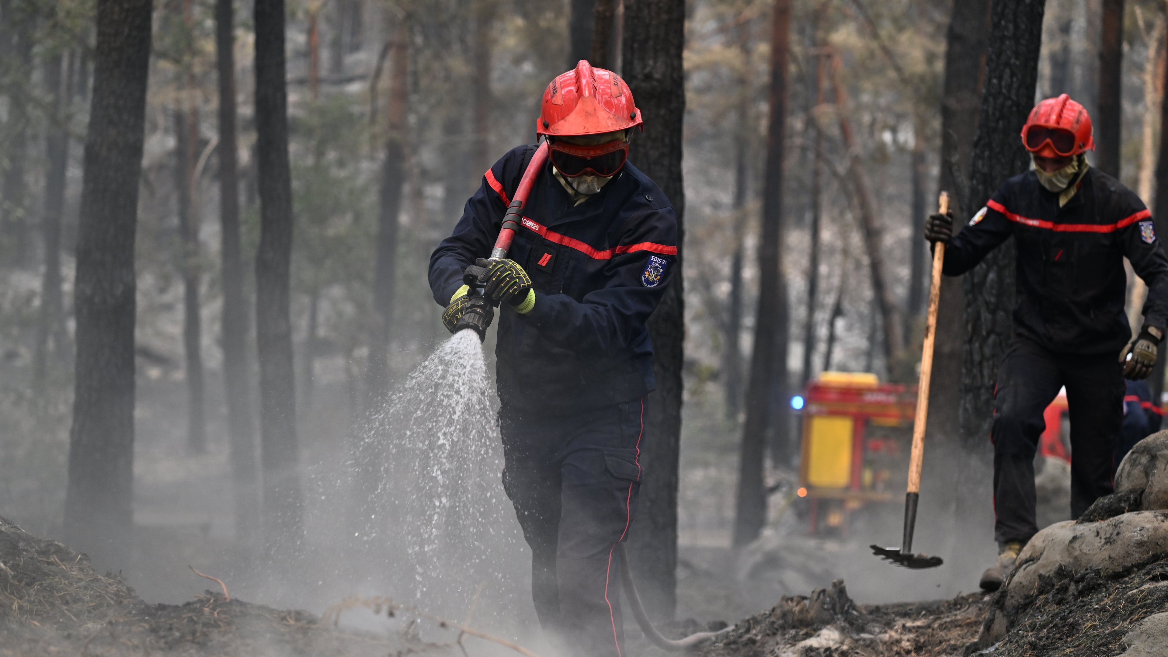 A firefighter sprays water after a wildfire in the region of the Fontainebleau forest, south of Paris, France, Tuesday, July 14, 2026. (AP Photo/Emma Da Silva)