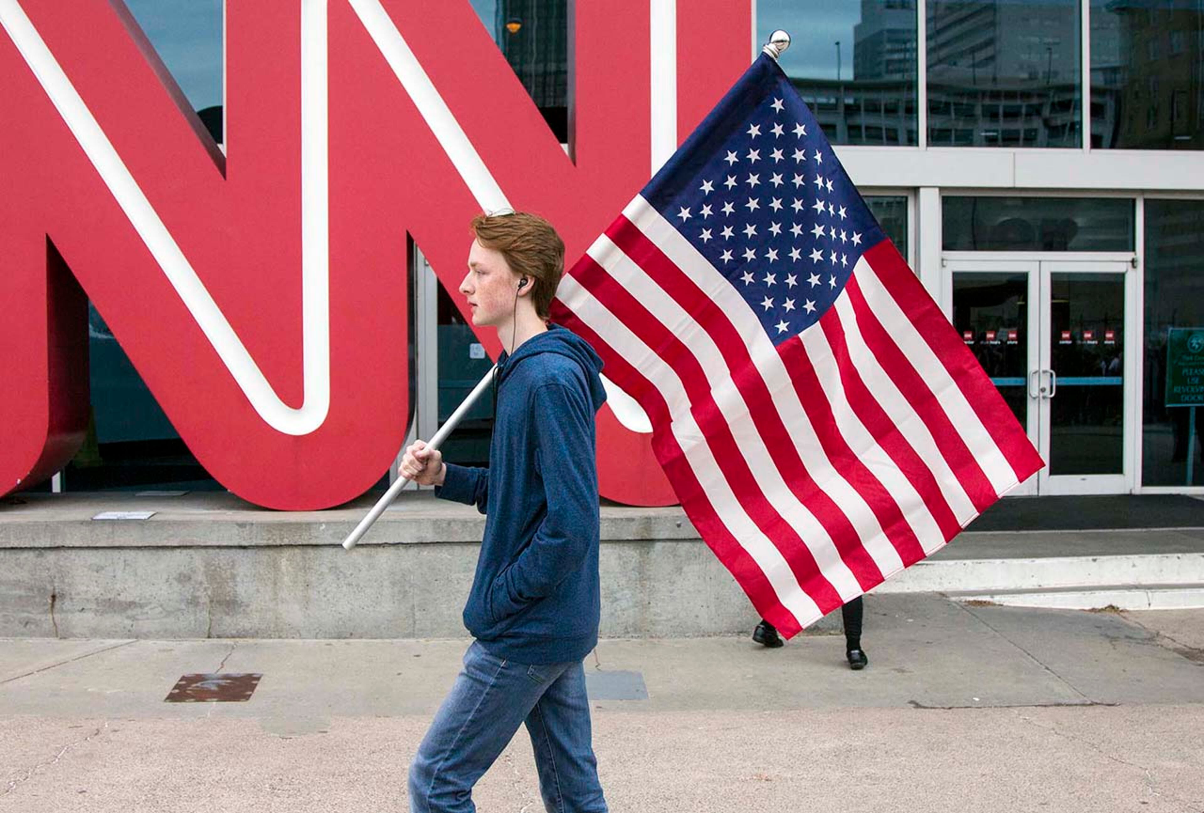 Tyler Bates, a student at South Paulding High, marches through the streets of Atlanta with an American flag during the March for our Lives event in Atlanta, Georgia, on Saturday, March 24, 2018. (REANN HUBER/REANN.HUBER@AJC.COM)