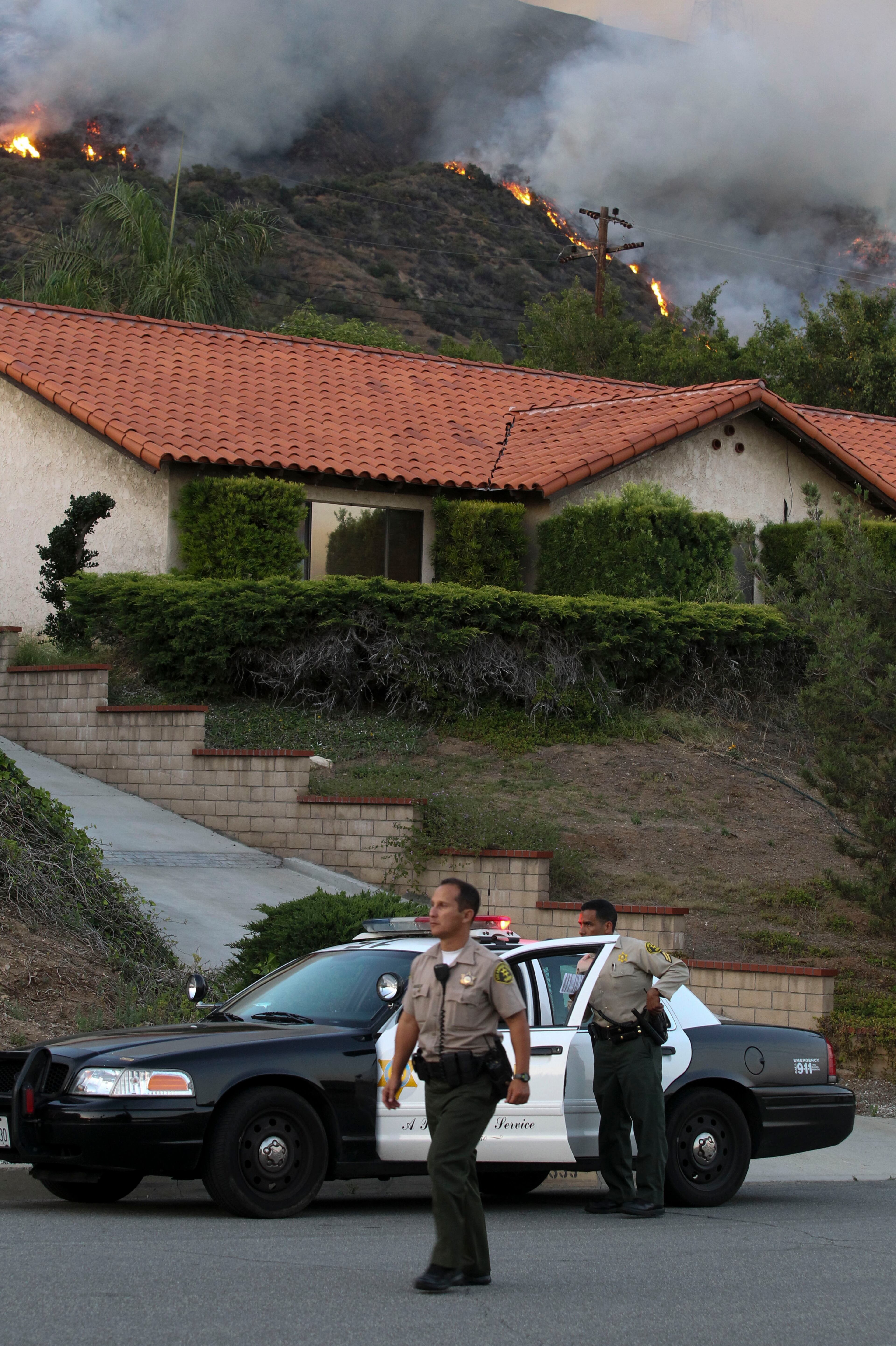 Police officers watch the wildfires in Azusa, Calif., Monday, June 20, 2016. (AP Photo/Ringo H.W. Chiu)