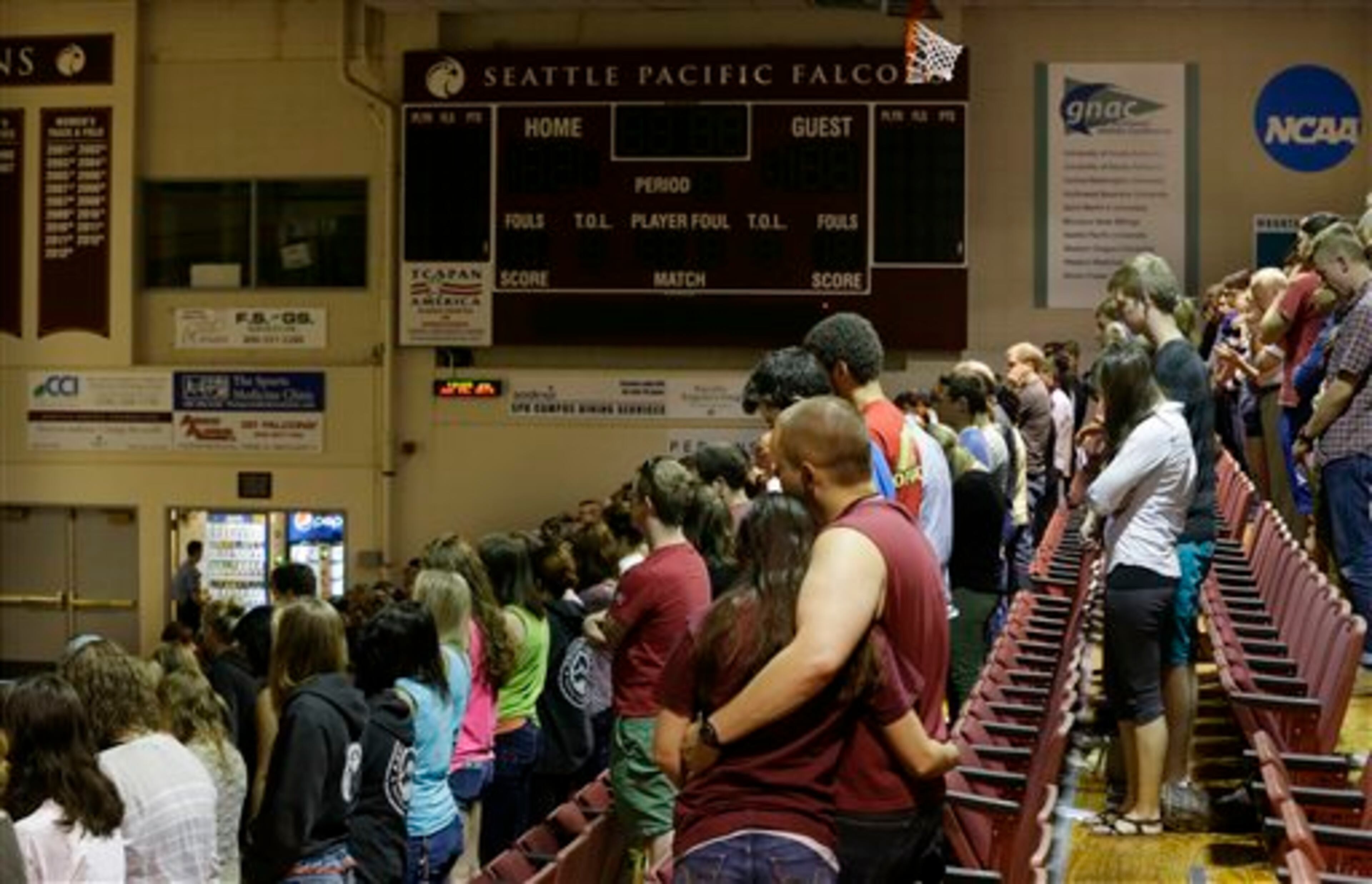 Students and other attendees stand in prayer in Royal Brougham Pavilion, which was being used as an overflow site for a broadcast of a prayer service at Seattle Pacific University Friday, June 6, 2014 in Seattle. The service was held a day after a fatal shooting at the school. (AP Photo/Ted S. Warren)