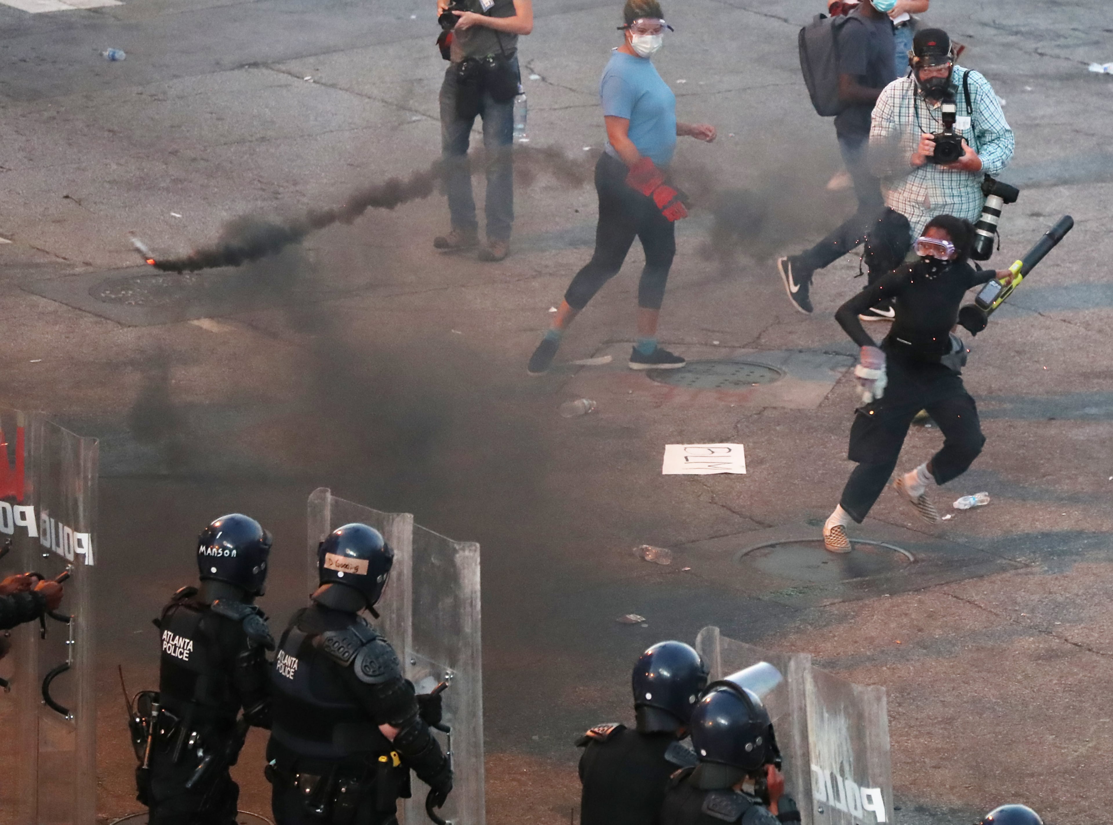 060220 Atlanta: A protesters throws a burning object at advancing law enforcement officials on Centennial Olympic Park Drive at Olympic Park after curfew during a fifth day of protests over the death of George Floyd on Tuesday, June 2, 2020, in Atlanta. Curtis Compton ccompton@ajc.com