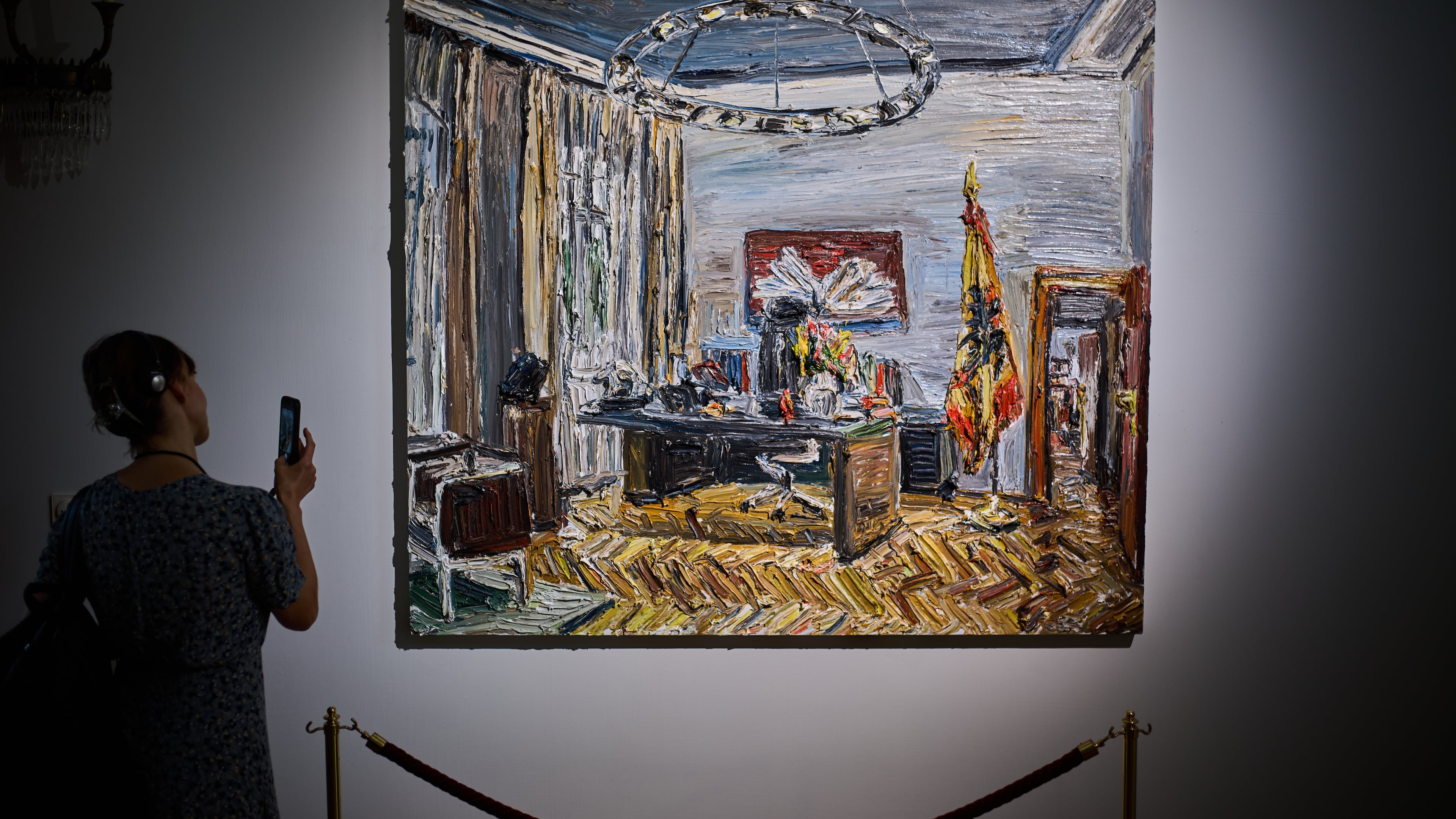 A person takes a photo of the painting "Im Buero des Bundespraesidenten" (In the office of the Federal President), by Christopher Lehmpfuhl, during the press preview of an exhibition of contemporary art at the German President's residency, Bellevue Palace, in Berlin, Germany, Monday, June 8, 2026. (AP Photo/Markus Schreiber)