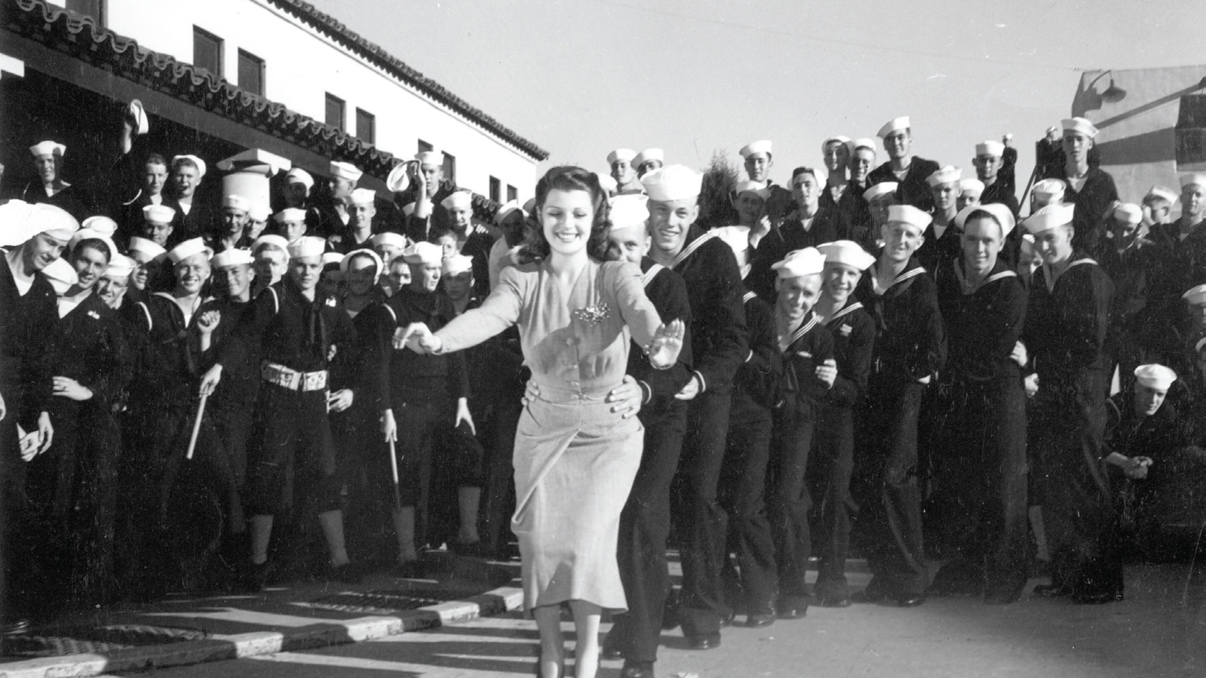 Rita Hayworth leads a line of sailors in the bunny hop at a USO show; Courtesy of Turner Classic Movies