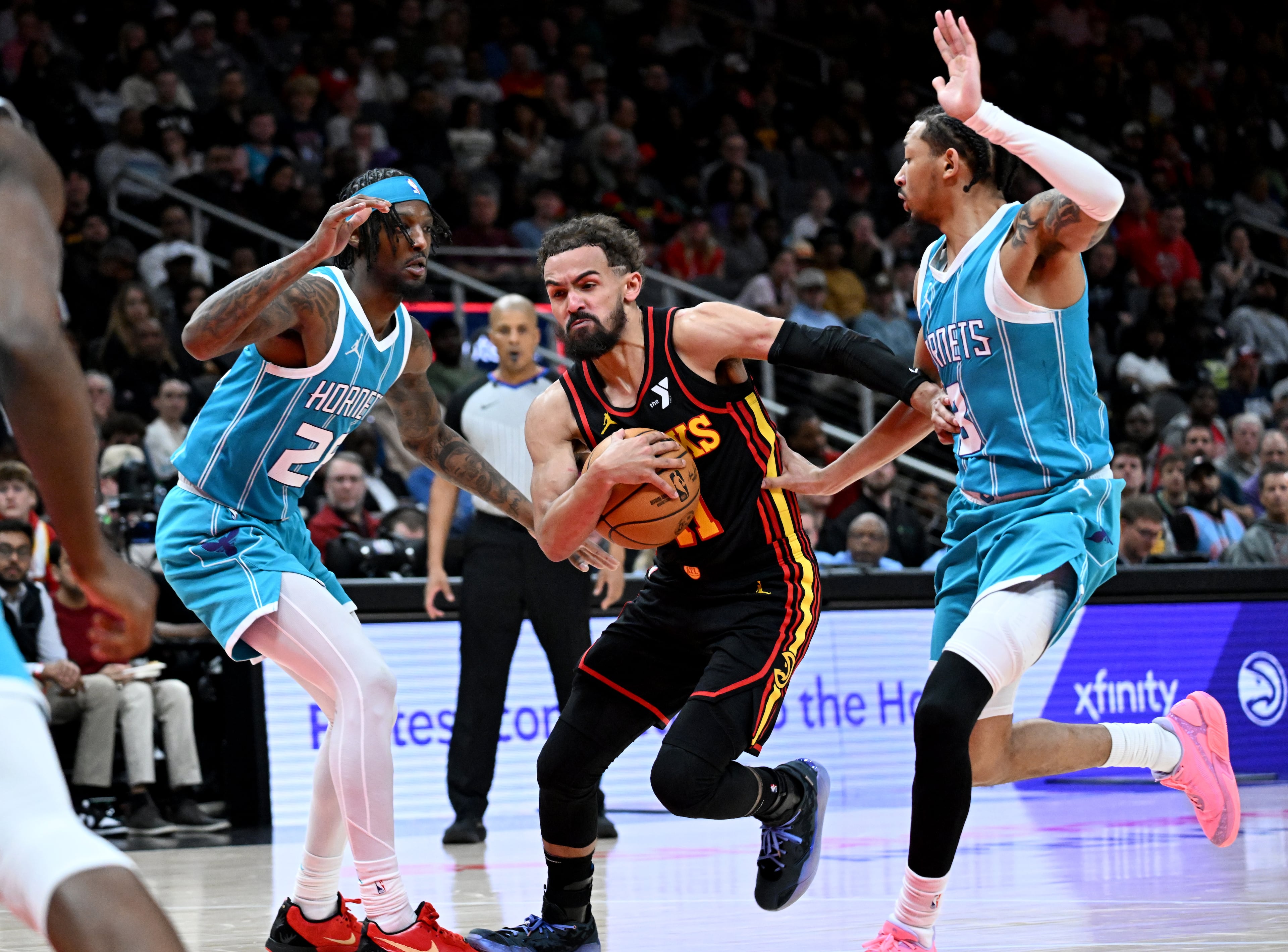 Atlanta Hawks guard Trae Young (11) drives against Charlotte Hornets guard Marcus Garrett (28) and Charlotte Hornets guard Nick Smith Jr. (8) during the first half in an NBA basketball game at State Farm Arena, Wednesday, March 12, 2025, in Atlanta. (Hyosub Shin / AJC)