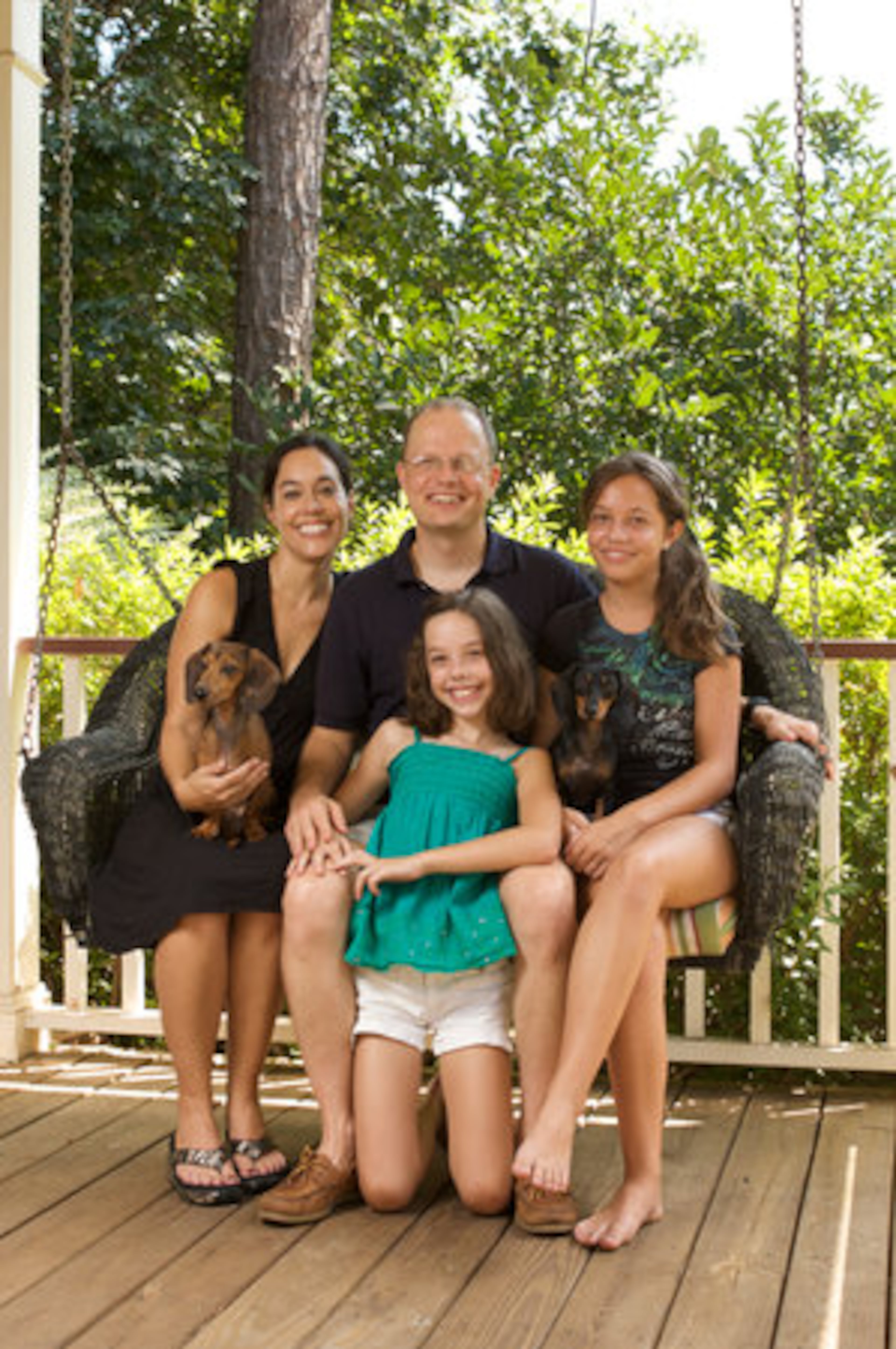 Laura and Todd Strickland sit on their front porch swing with daughters Kate, 10, (center) and Madi, 12, and dachshunds, Saucy (left) and Hershey. The family enjoys the active lifestyle Peachtree City offers with golf cart paths that lead to the school and allow Todd to bike five miles to work every day.