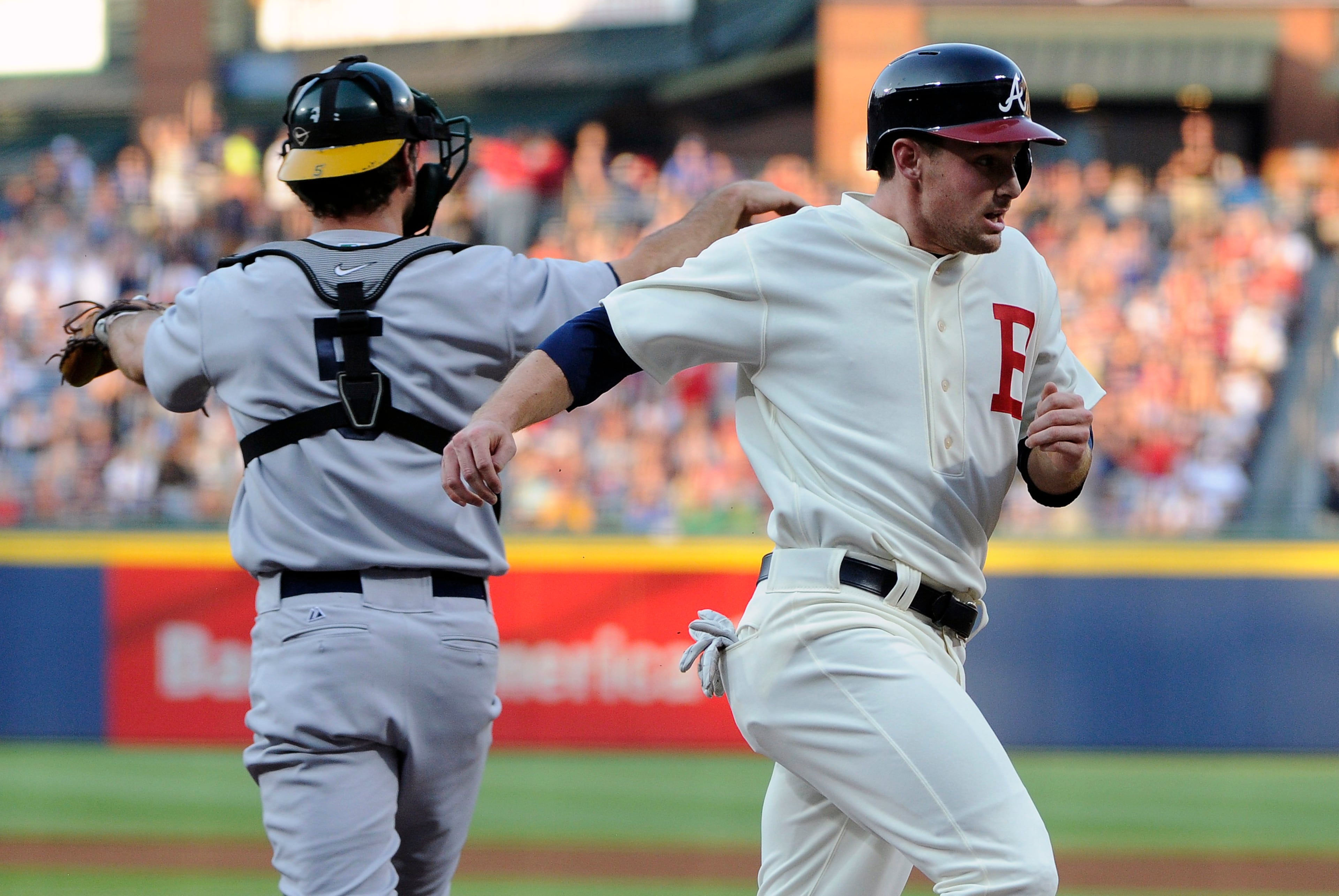 Atlanta Braves' Phil Gosselin, right, scores past Oakland Athletics catcher John Jaso (5) on Freddie Freeman's double during the first inning of a baseball game Saturday, Aug. 16, 2014, in Atlanta. (AP Photo/David Tulis)