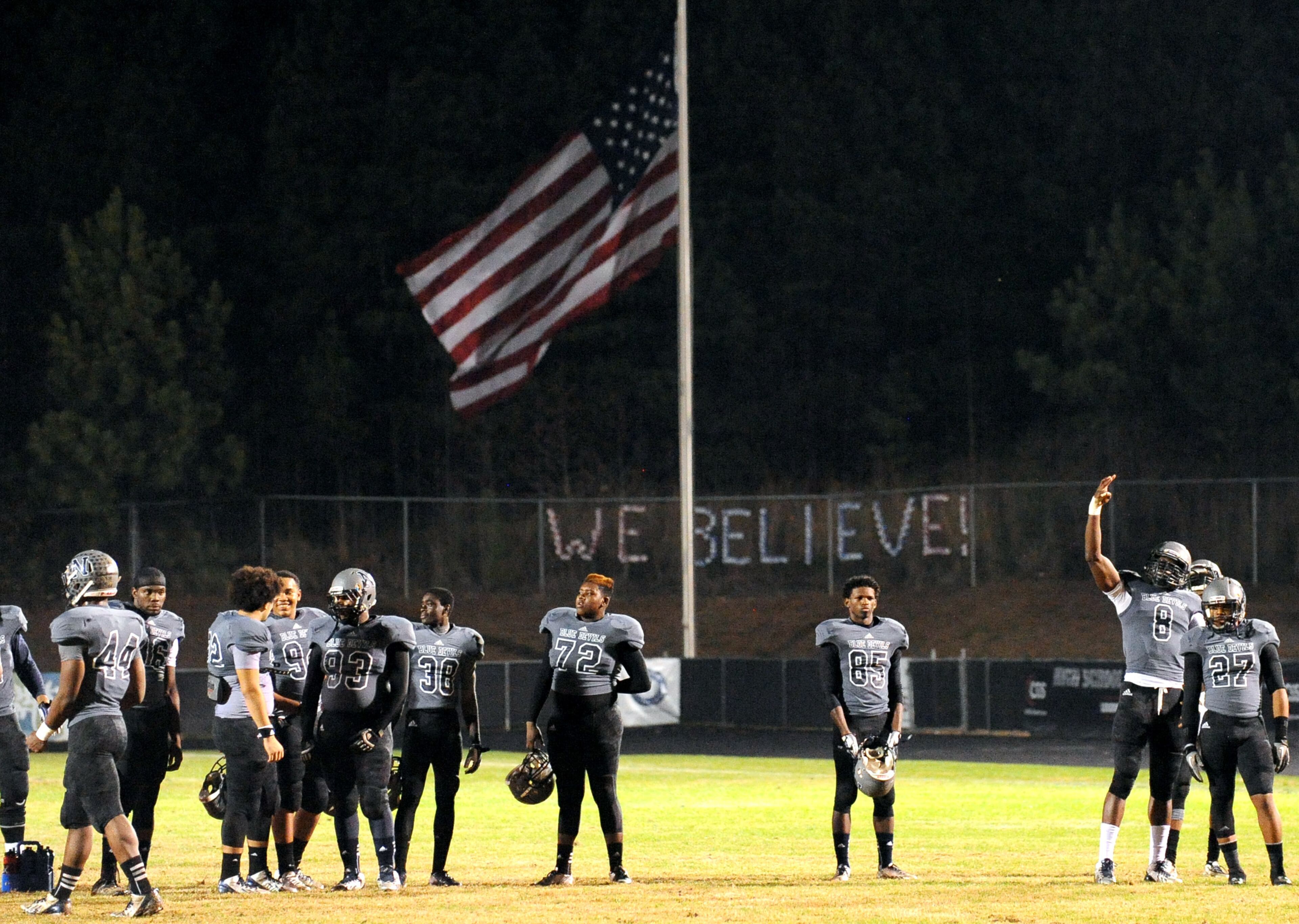 The US flag flies at half staff behind Norcross players to honor former South African President Nelson Mandela as the team warms up for their AAAAAA semifinal high school football game against Colquitt County at Blue Devil Stadium on Friday, Dec. 6, 2013, in Norcross, Ga.
